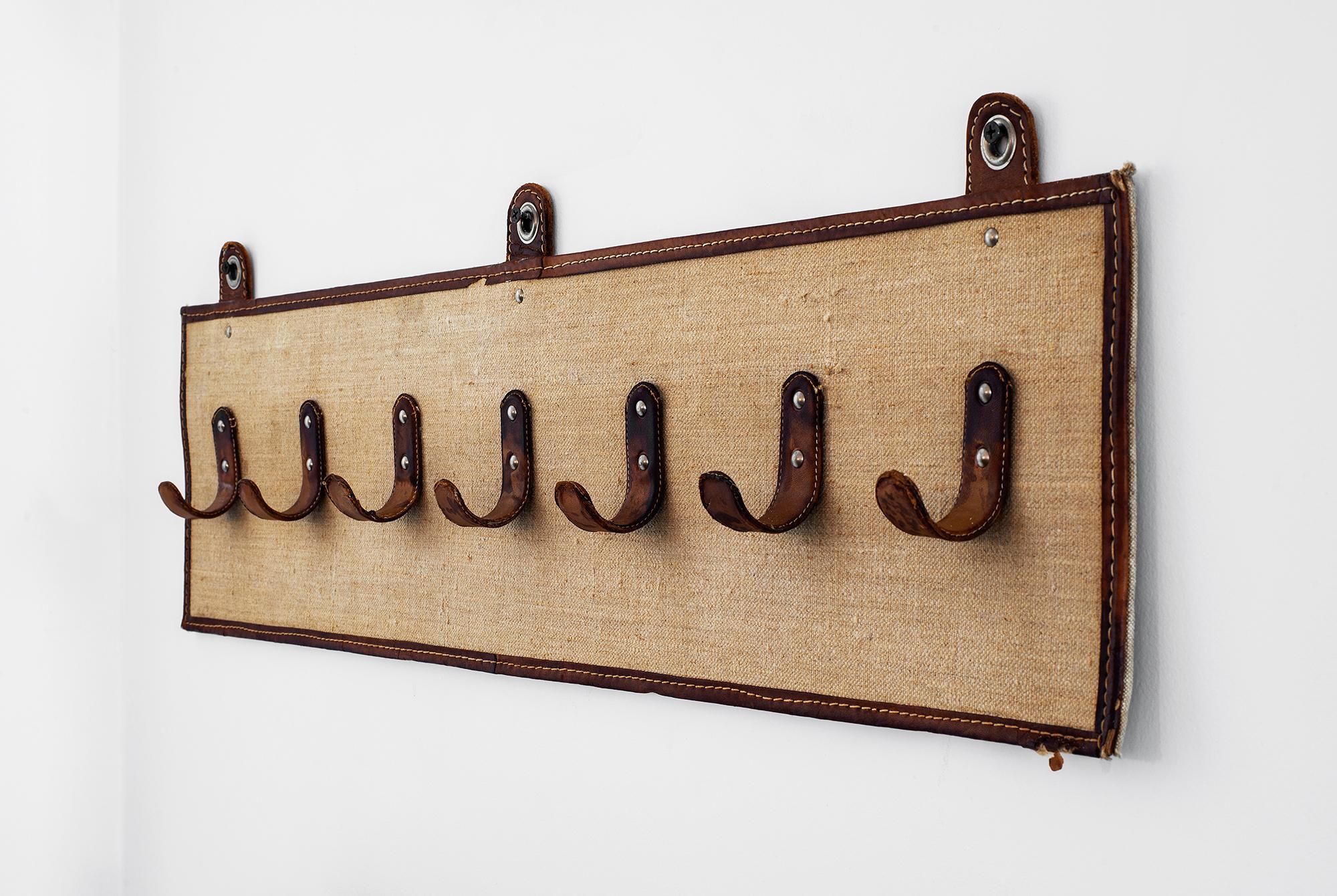 Fantastic coatrack in the style of Jacques Adnet with 7 leather hooks on woven seagrass with leather framed trim and brass detail. 
 