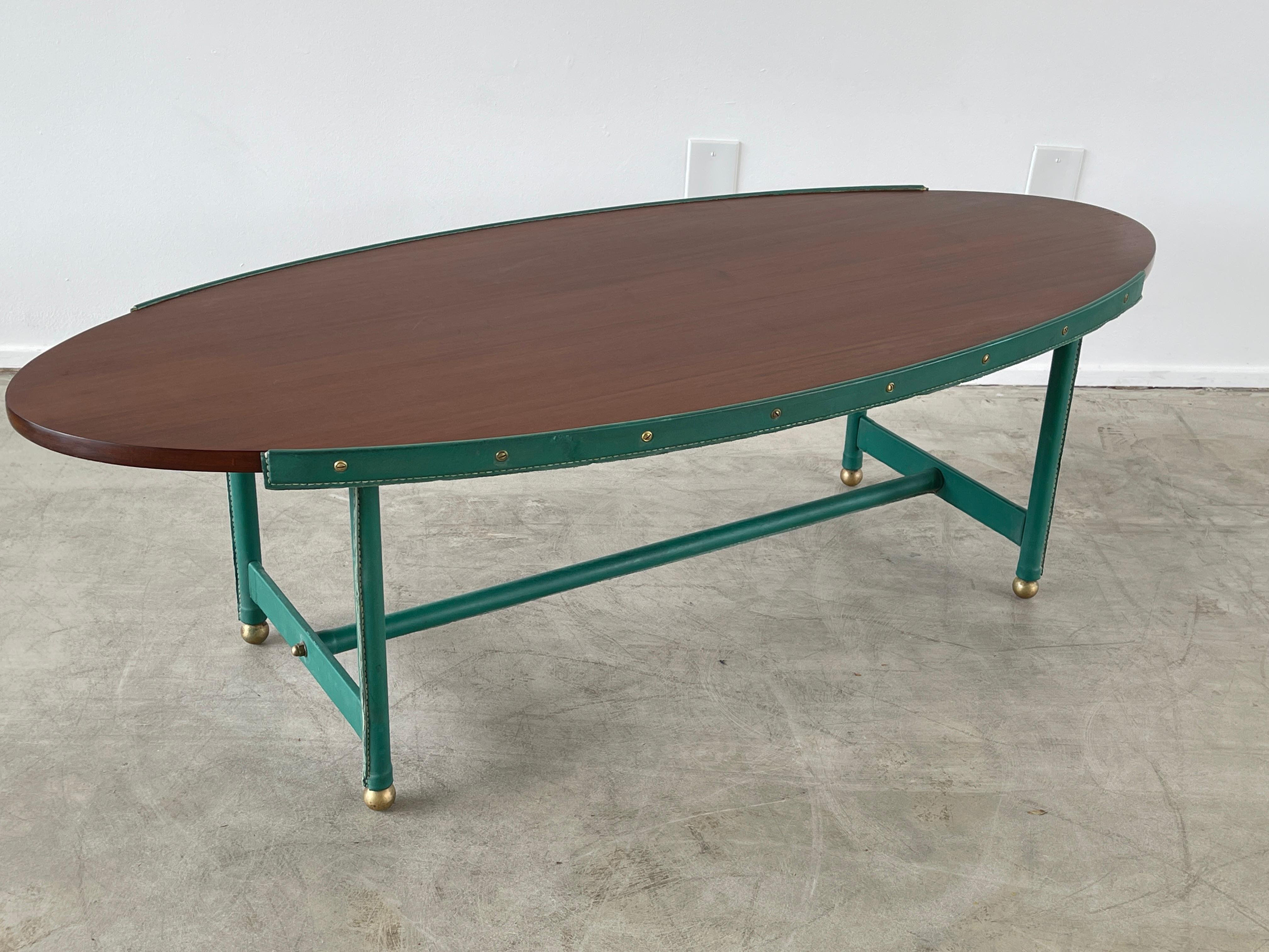 Rare table basse de forme elliptique Jacques Adnet en cuir vert d'origine / plateau en bois d'acajou et signature bambou en laiton et surpiqûres contrastées. 
Une pièce incroyable.