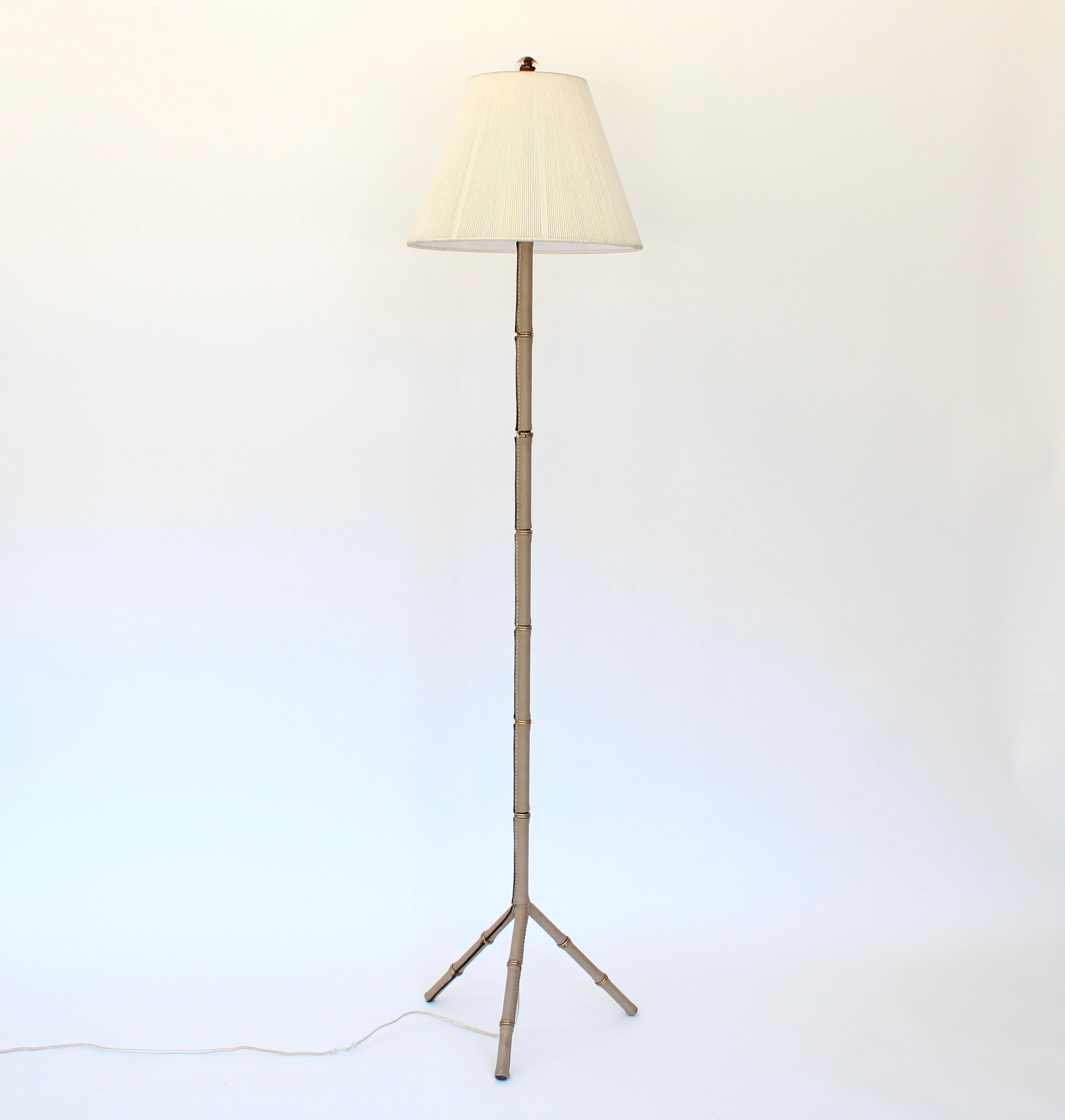 Lampada da terra in pelle color crema del designer francese Jacques Adnet con stelo in pelle di bambù e ottone e cuciture a contrasto. Pelle fino alla base del treppiede.
Appena ricablata con un nuovo paralume in lino color crema. Bellissimo finale