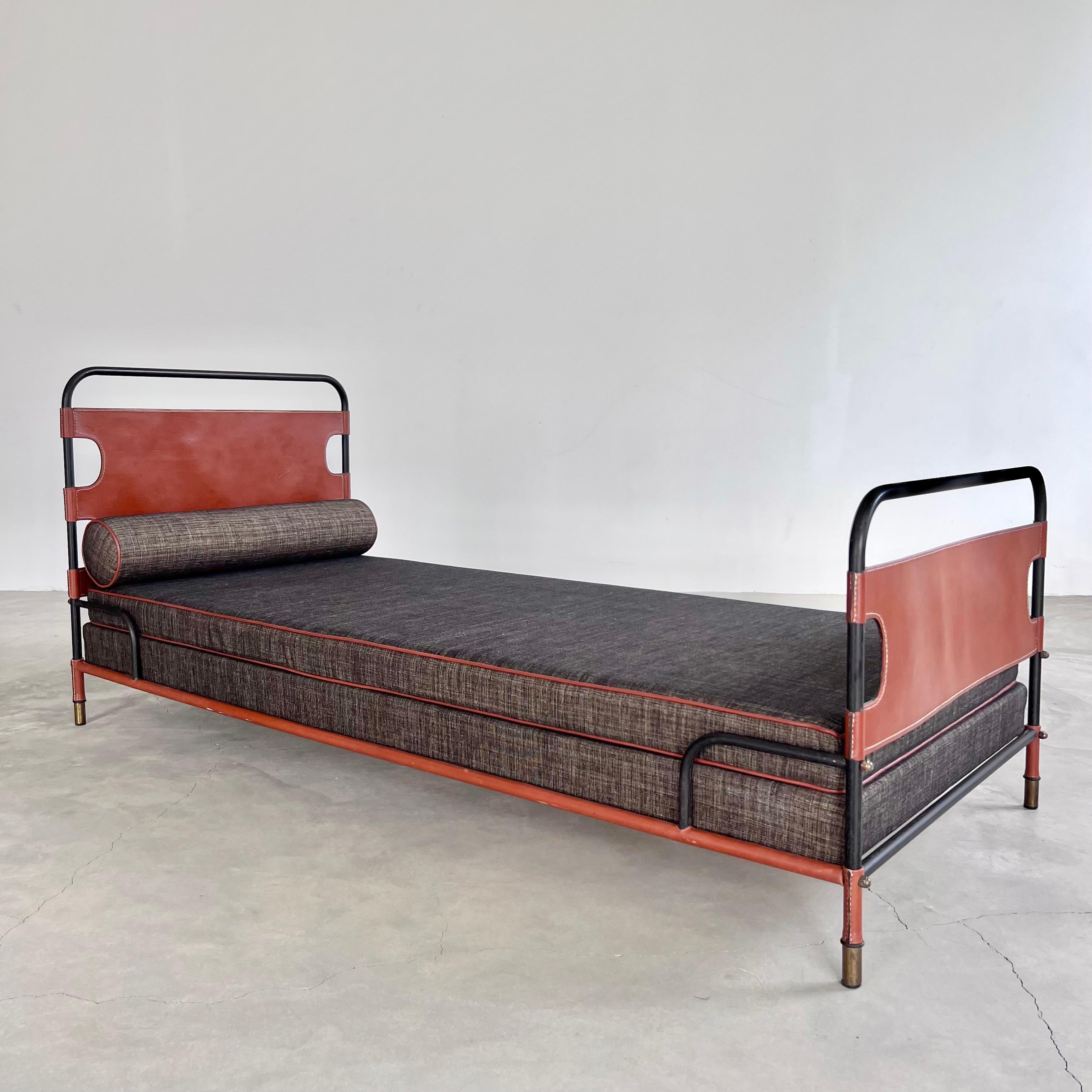 Exceptional leather and oak daybed by Jacques Adnet. The entire frame is wrapped in dark green leather with signature Adnet contrast stitching and brass hardware. Cane style paneling on all sides. Only the two crossbars underneath the bed are not