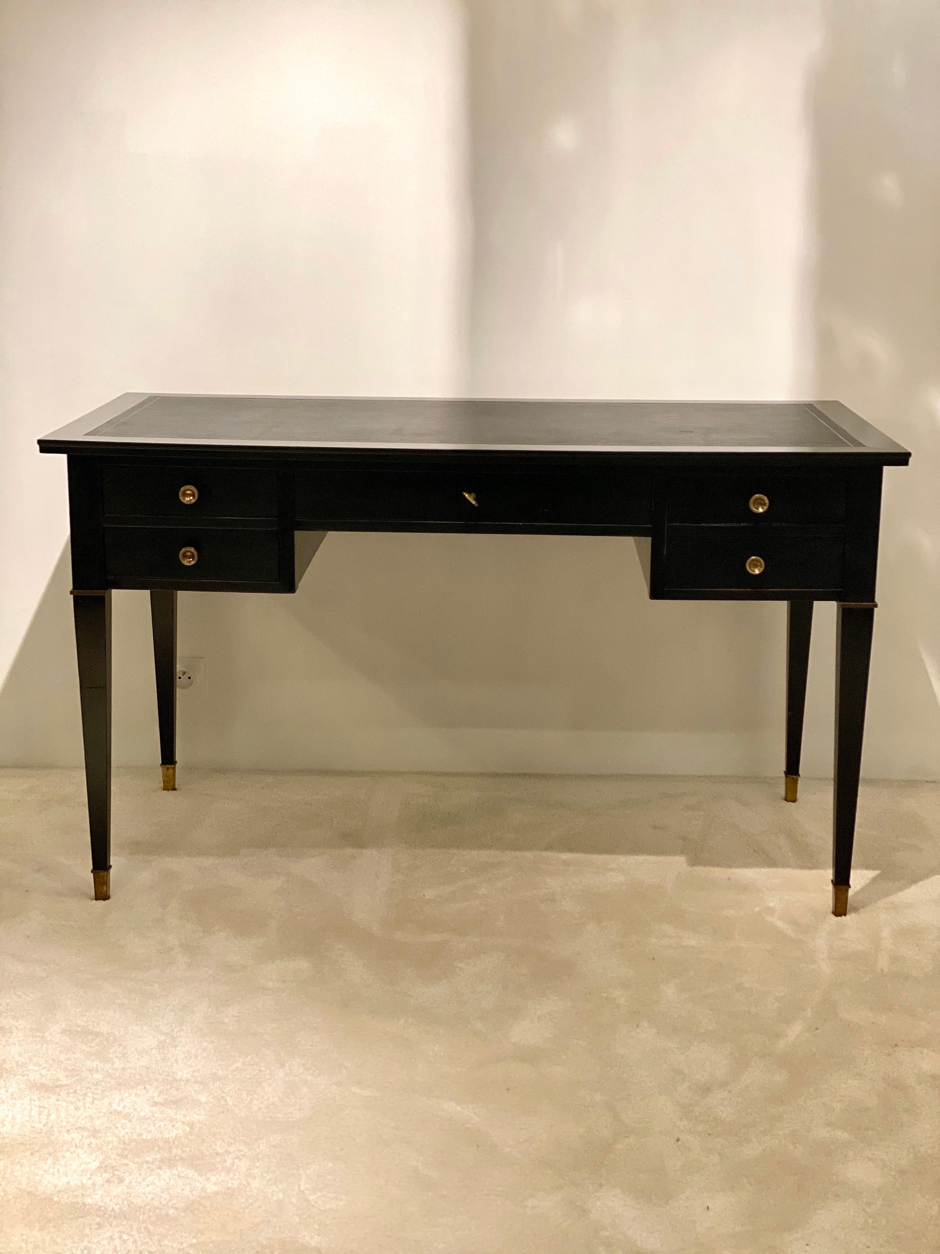 Jacques Adnet was a French designer who was well known for his leather furniture and elegant lines.
This black wood desk has a modern vibe, beautiful volume, top covered in black leather and brass buttons to give contrast: a touch of luxury for any
