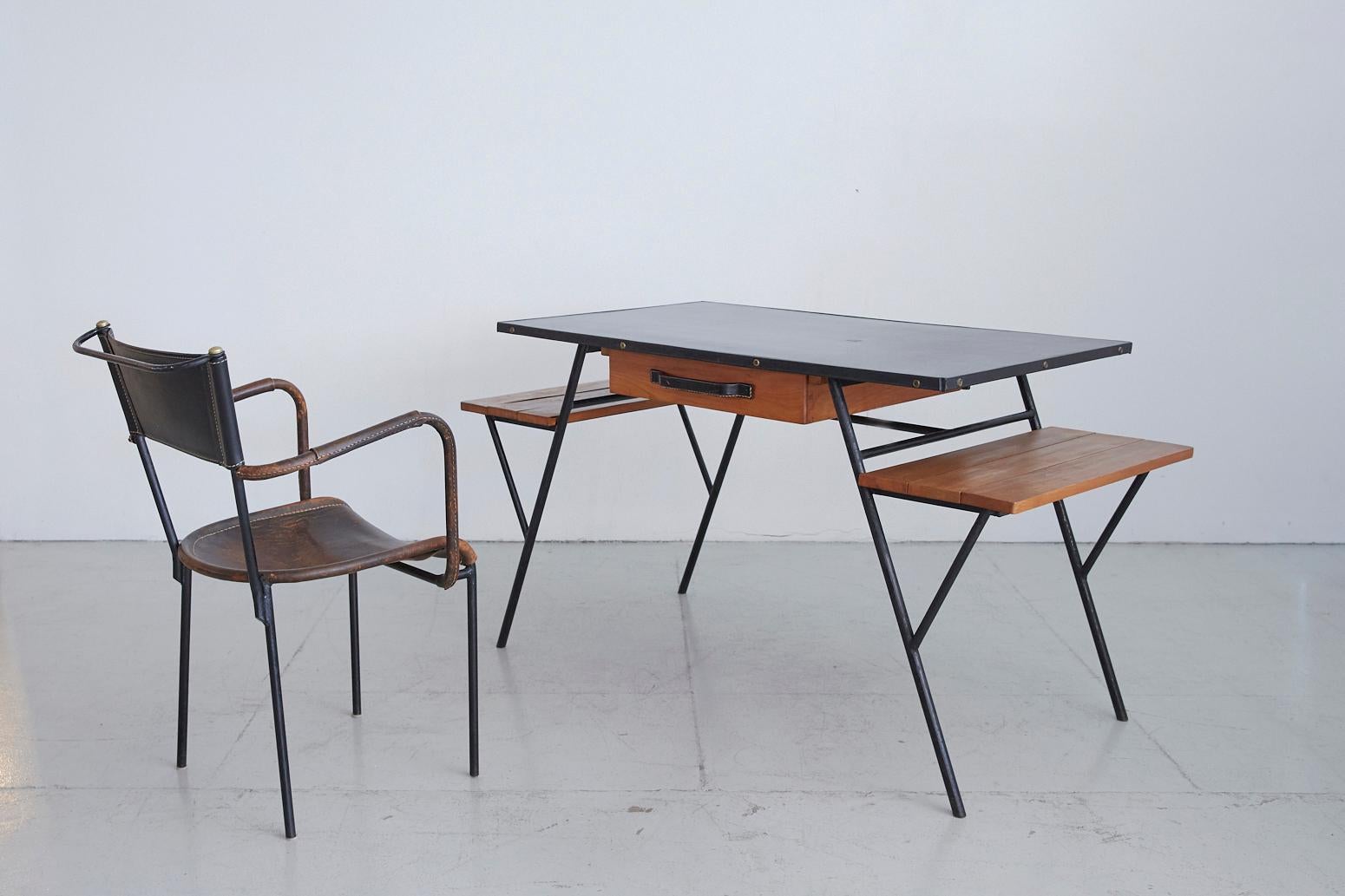 Rare Jacques Adnet desk and armchair. Desk has black leather top, oakwood drawer with leather handle, two oak open side shelves and black lacquered metal legs. Chair has great two-tone leather with a saddle brown seat and arms showing fantastic age