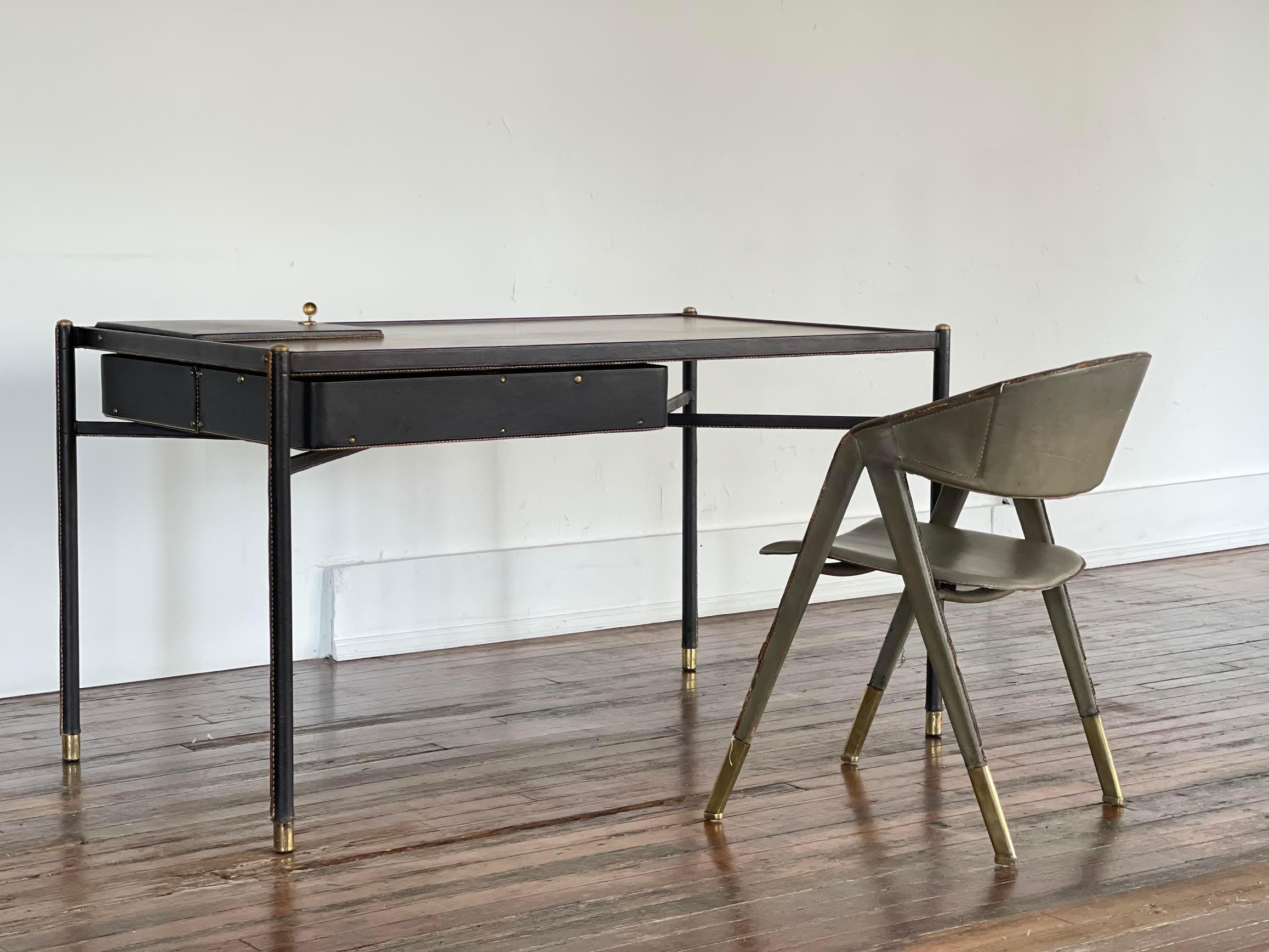 This is an exceptional example of a rare Jacques Adnet writing desk (circa 1950) featuring signature Adnet detailing including; black saddle stitched leather wrapped over a steel frame, patinaed brass hardware, and inset solid Cherry wood top. This
