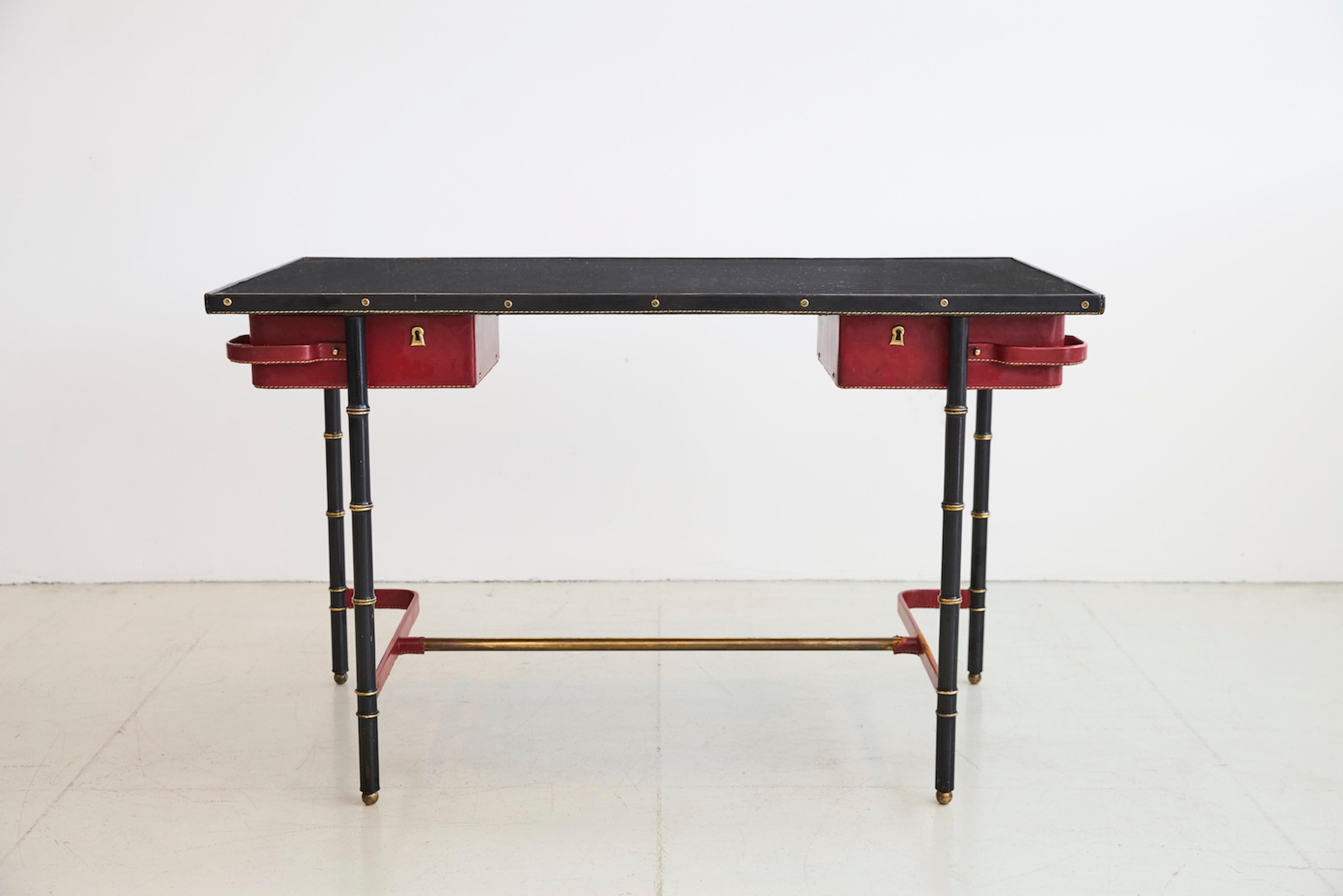 Rare Jacques Adnet desk with red leather pivoting drawers in red leather, signature brass bamboo frame and black leather top.
 