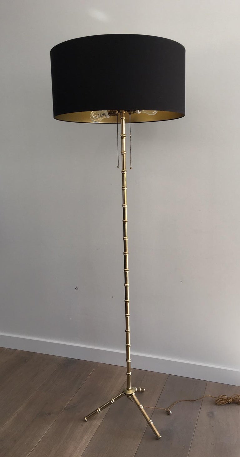 This floor lamp is made of brass. It is imitating faux-bamboo. It is heavy and the quality is really good. This is a model by famous French designer Jacques Adnet, made circa 1940. The shade has been remade in black shintz, gold inside.
 