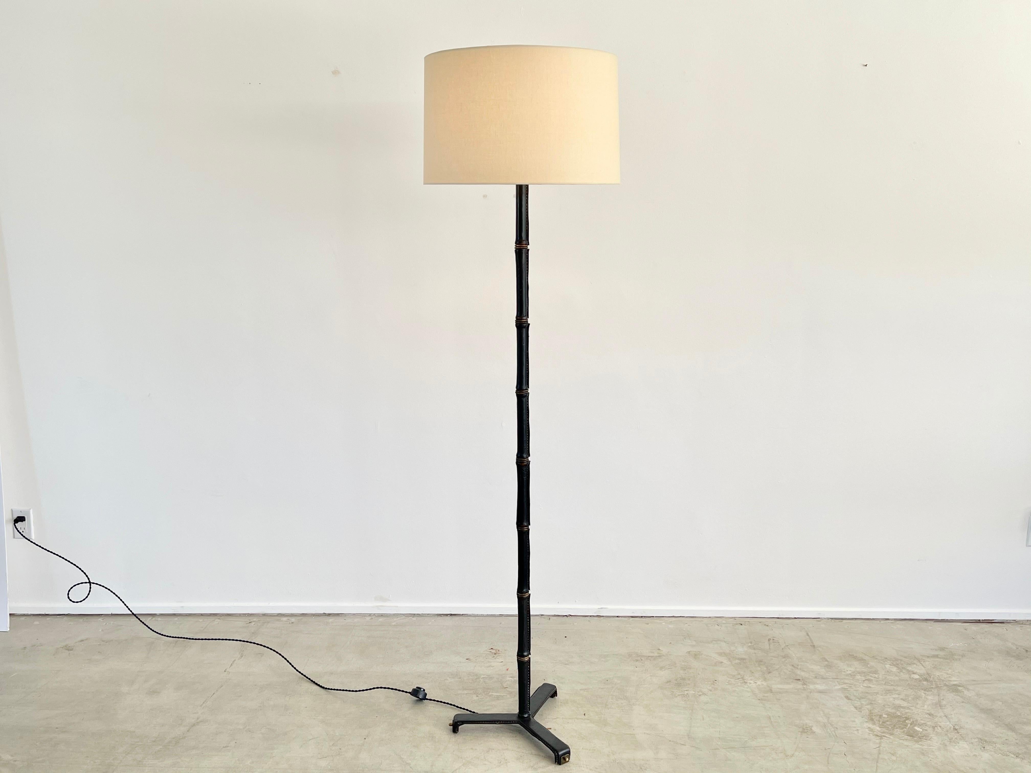 Incredible leather wrapped floor lamp with signature bamboo leather and brass stem and contrast stitching. Leather all the way down to the tripod base. 
Newly rewired with new silk shade.