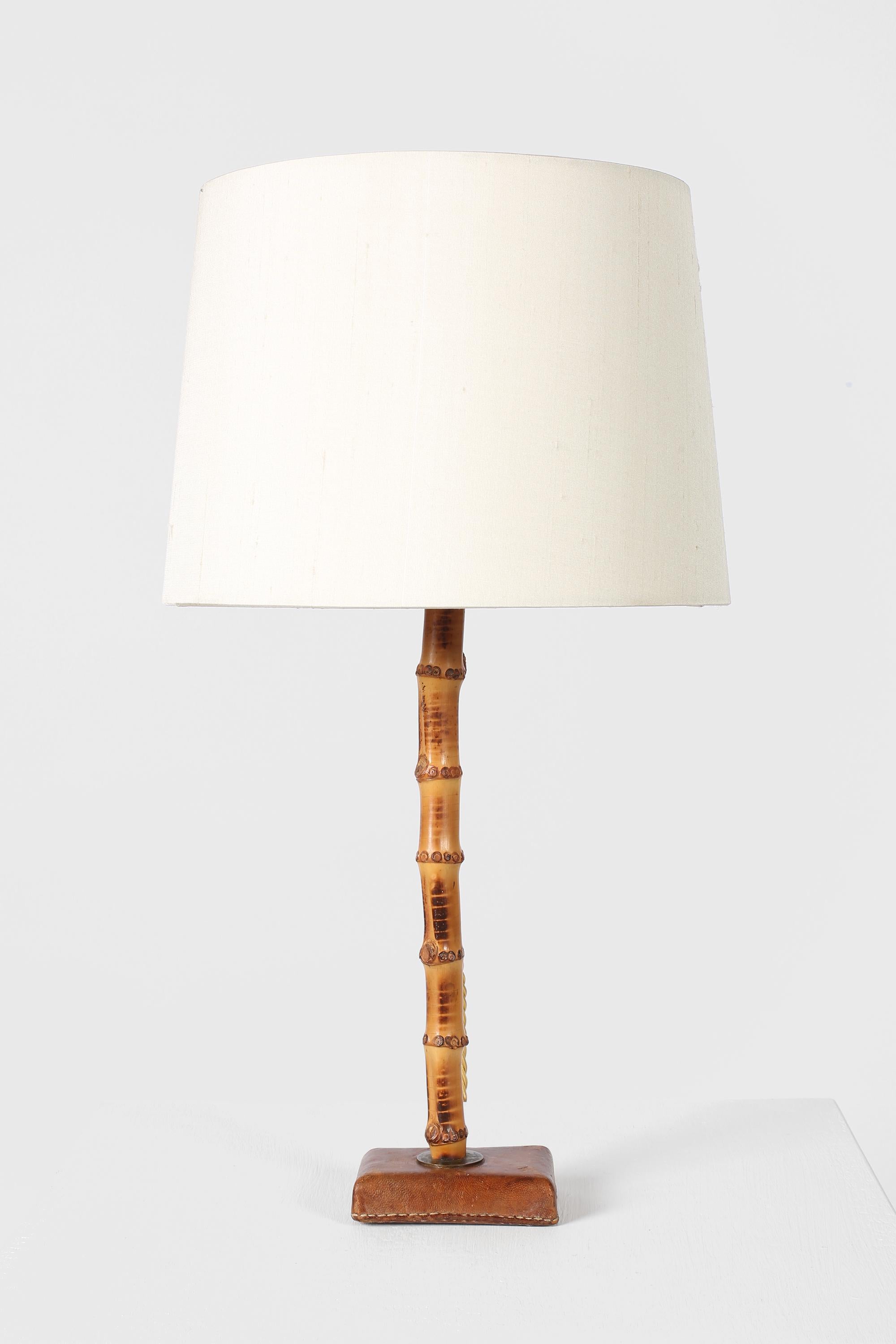A rare bamboo and saddle-stitched cognac leather table lamp by Jacques Adnet (1900-1984). French, c. 1950s. Supplied with an off-white dupion silk shade.