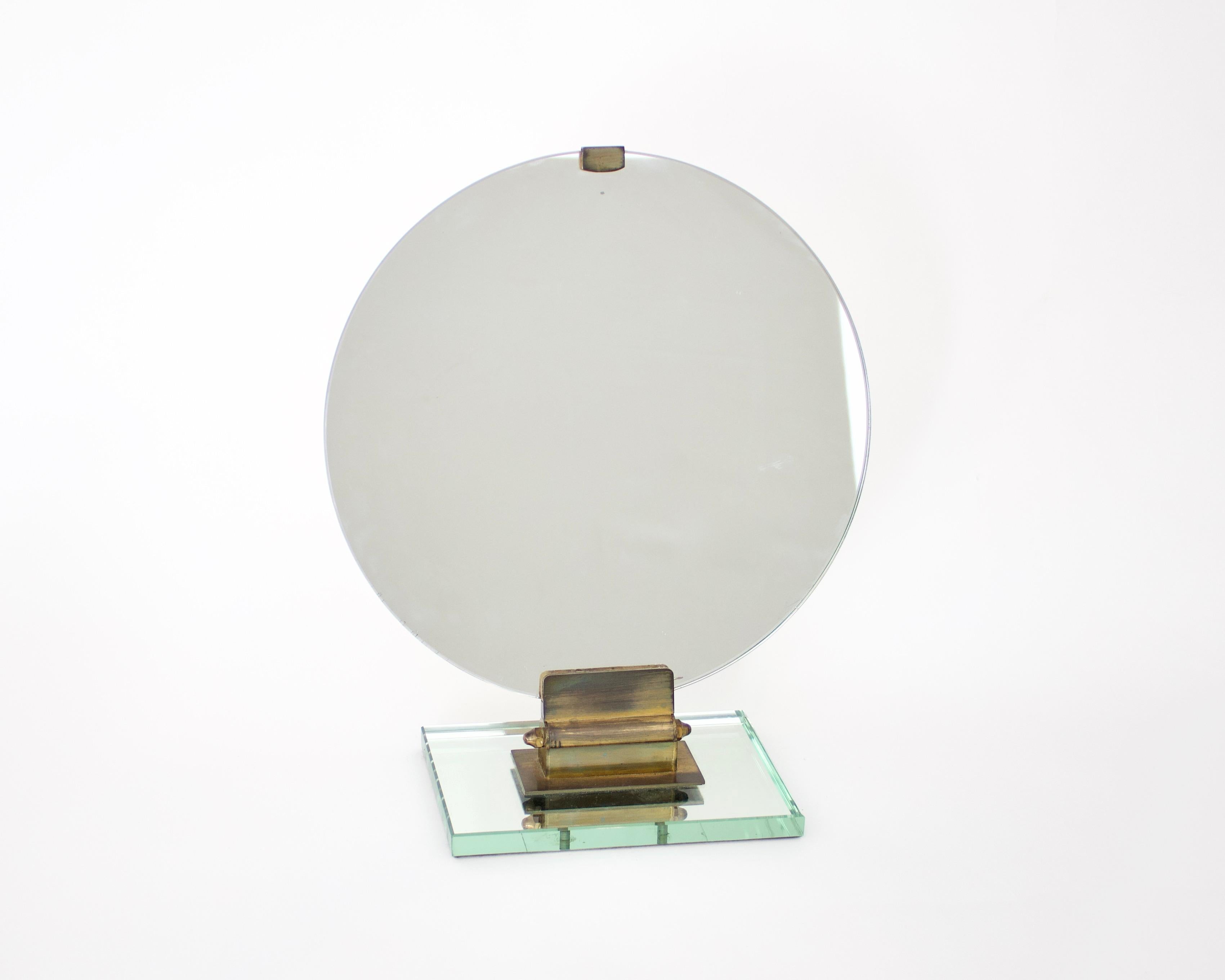 A chic Jacques Adnet French vanity mirror or dresser mirror in original glass with bronze base and details sitting on a perfect beveled fotnatna arte mirrored glass base. No chips or flaws to the mirror. The mirror is 13” diameter. 
15.75