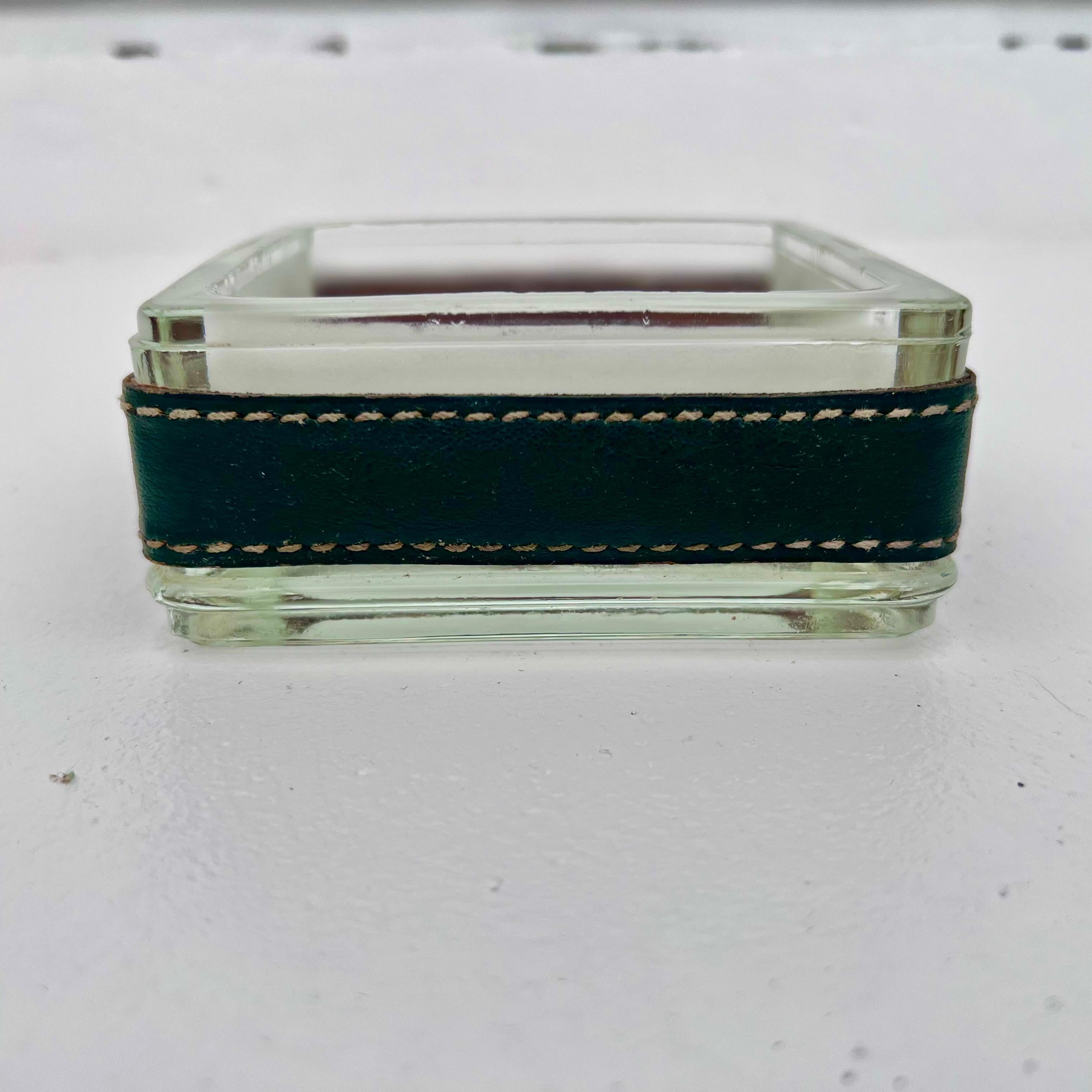 Handsome green leather and frosted glass ashtray from the 1950s by seminal French Art Deco modernist designer Jacques Adnet. The inside part of the glass receiver is frosted and surrounded with a green textured leather strap with Adnet's signature