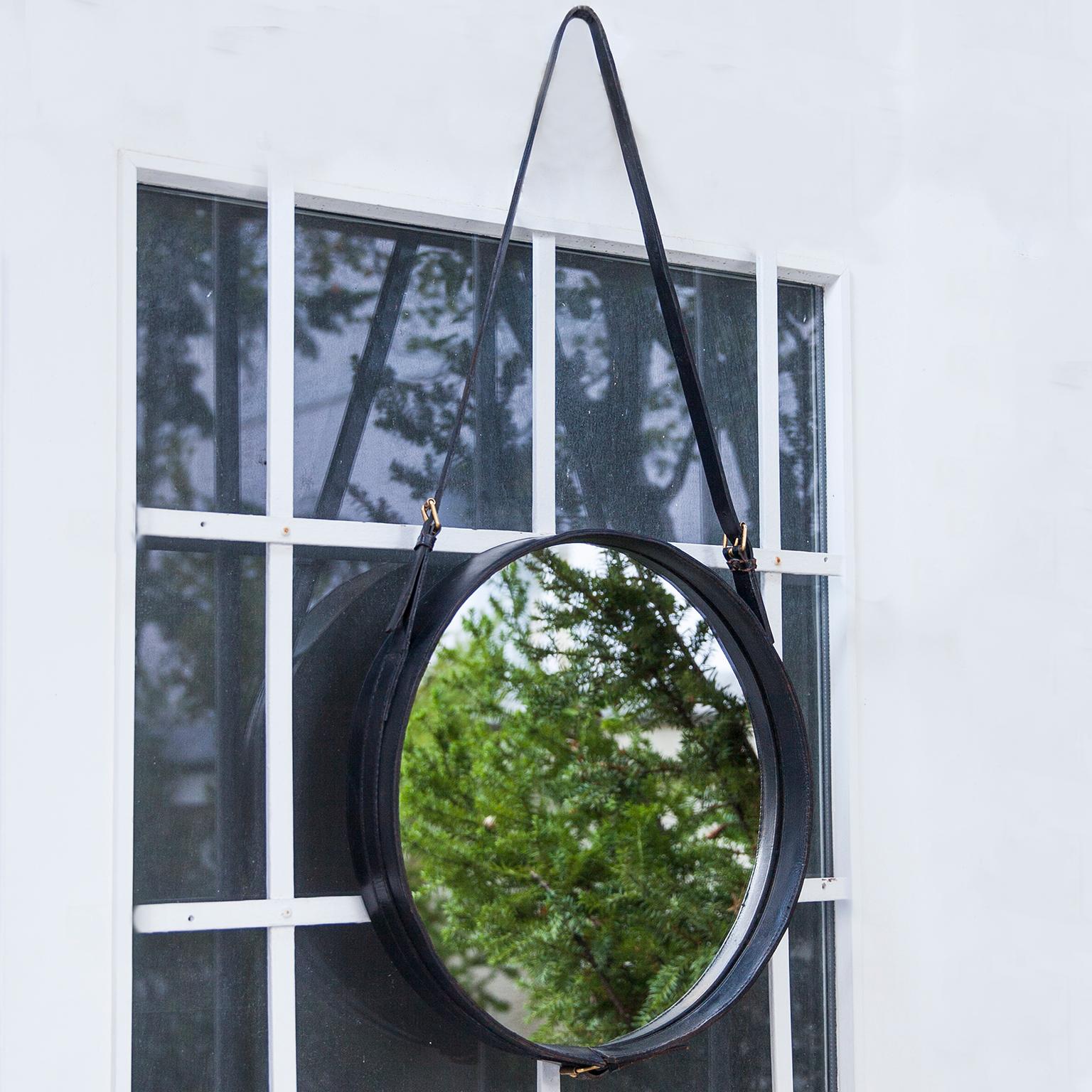 Elegant round wall mirror designed by French designer Jacques Adnet in 1950, Jacques Adnet developed a collection of furniture and accessories for Hermès, this mirror was part of this collection. Black handstitched leather frame with straps and