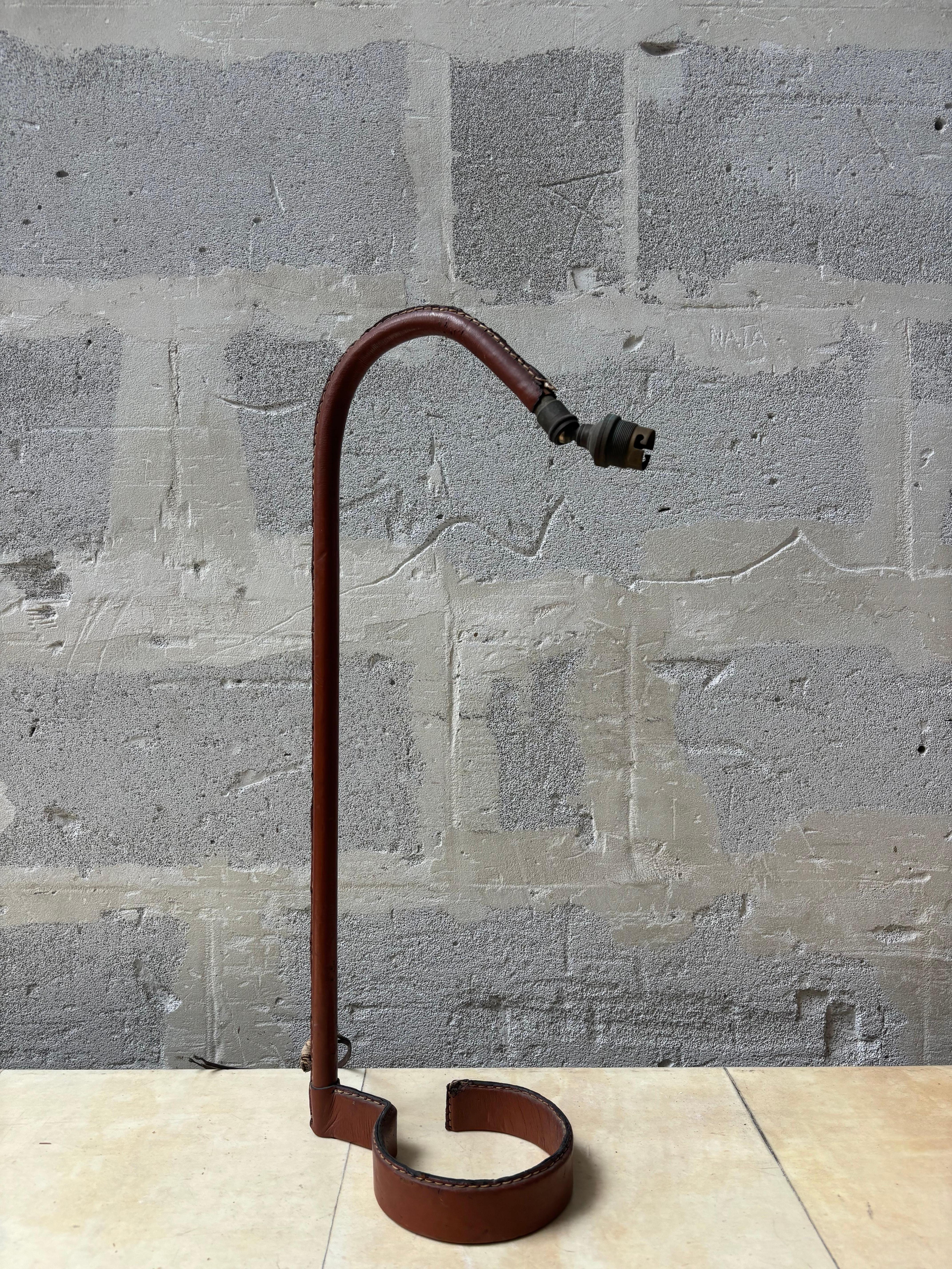 Jolie lampe par Jacques Adnet en cuir piqué sellier brun. 
Jolie forme. 