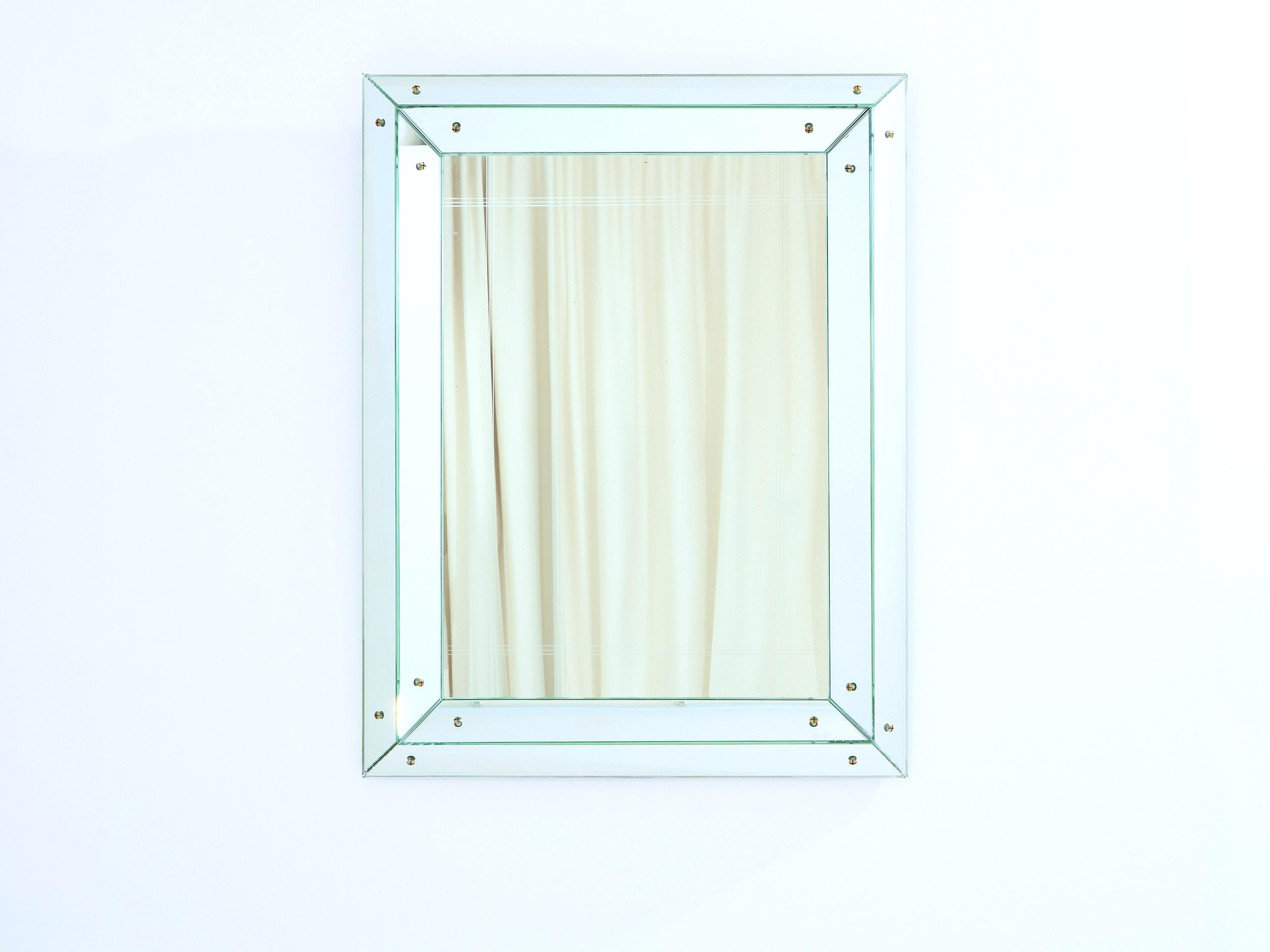 This beautiful Jacques Adnet parclose faceted mirror, made in 1947, has aged gracefully. Its patina, with original glass, brass screws and hardware, now imbues it with a lovely romantic feel. Dated on the back.