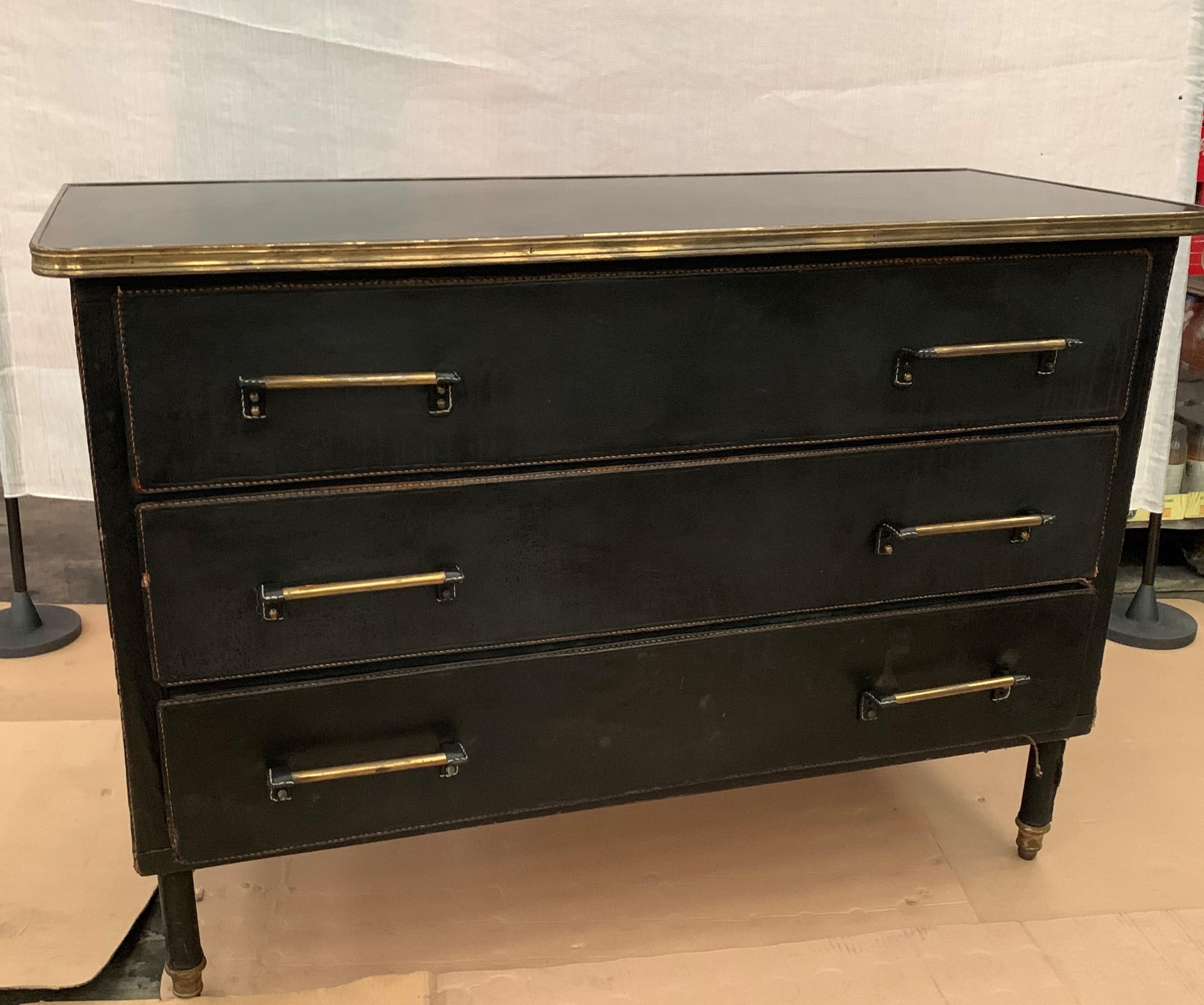 Very rare black stitched leather commode designed by Jacques Adnet in France in 1950s. A large model, built on a structure in oak and saddle stitched leather wrapped on 3 sides. It has 3 large drawers with double handles in brass on the front. It is