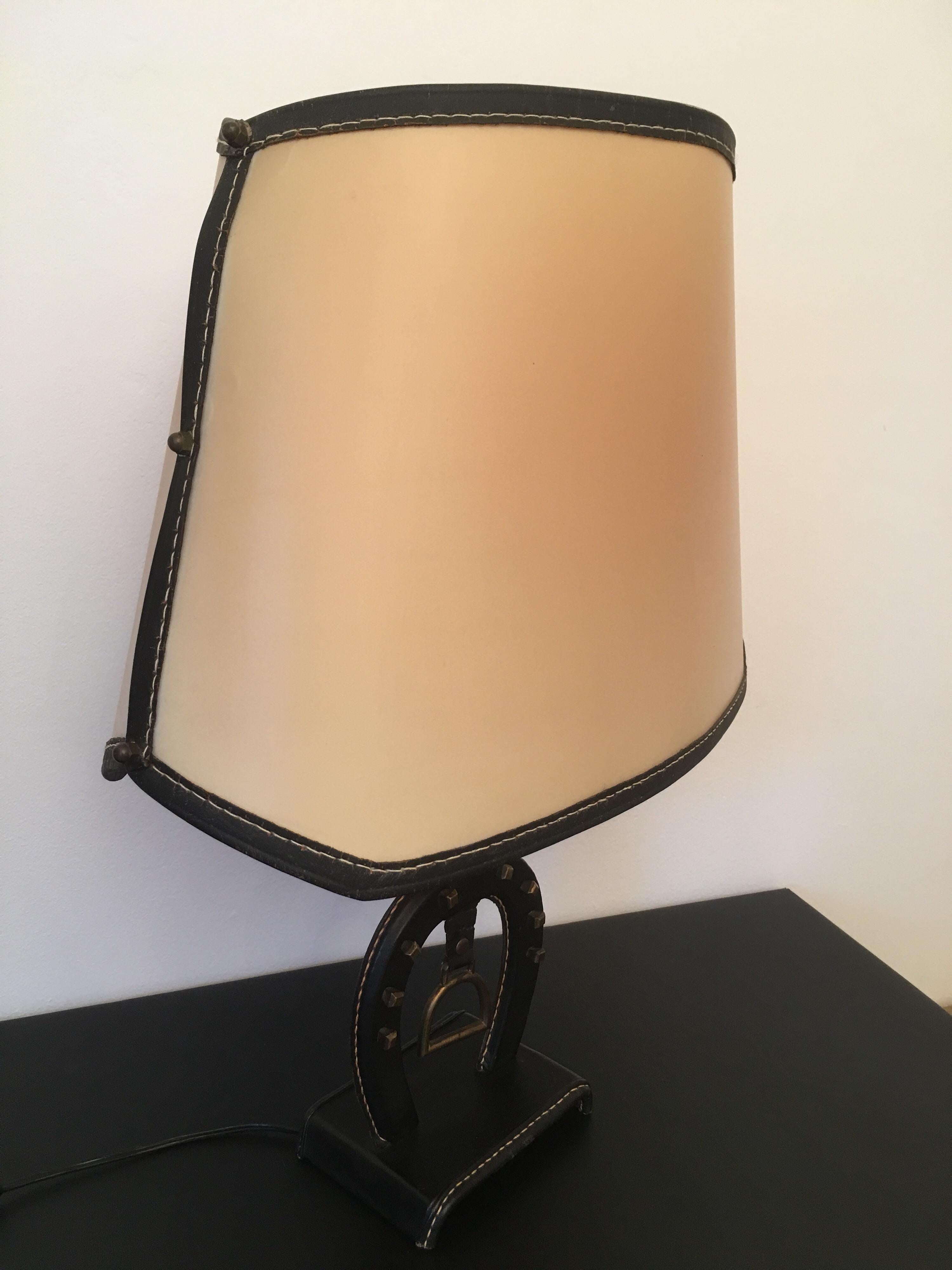 Large equestrian saddle-sttched leather table lamp designed by Jacques Adnet in France in 1950s.
Rare model entirely of origin with its particular lampshade
Original black leather and original rhodoid lampshade with some use of wear. Vintage
