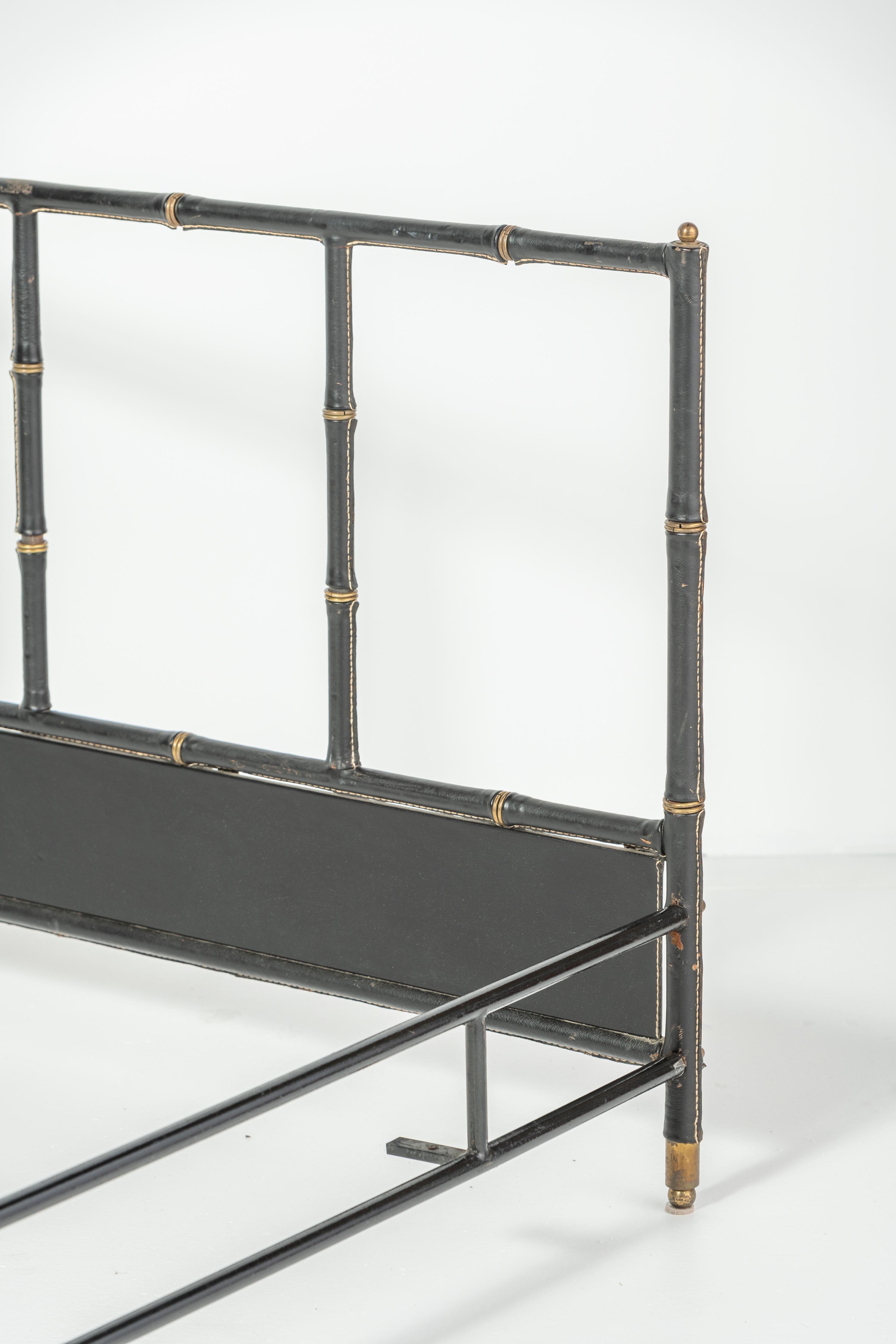 Elegant bed frame by French designer Jacques Adnet. Completely wrapped in black saddle leather. Characteristic stacked bamboo motif. Signature Jacques Adnet contrast-stitching. Holds a full size mattress. 