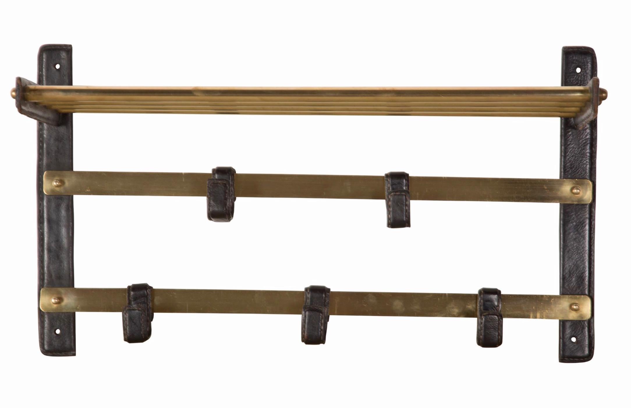 Stunning Adnet style leather and brass coat rack. Right and left wall brackets wrapped in leather. Horizontal brackets also wrapped in leather. 5 leather wrapped hooks arranged on brass bars. Brass shelf on top. Extremely practical piece. Very good