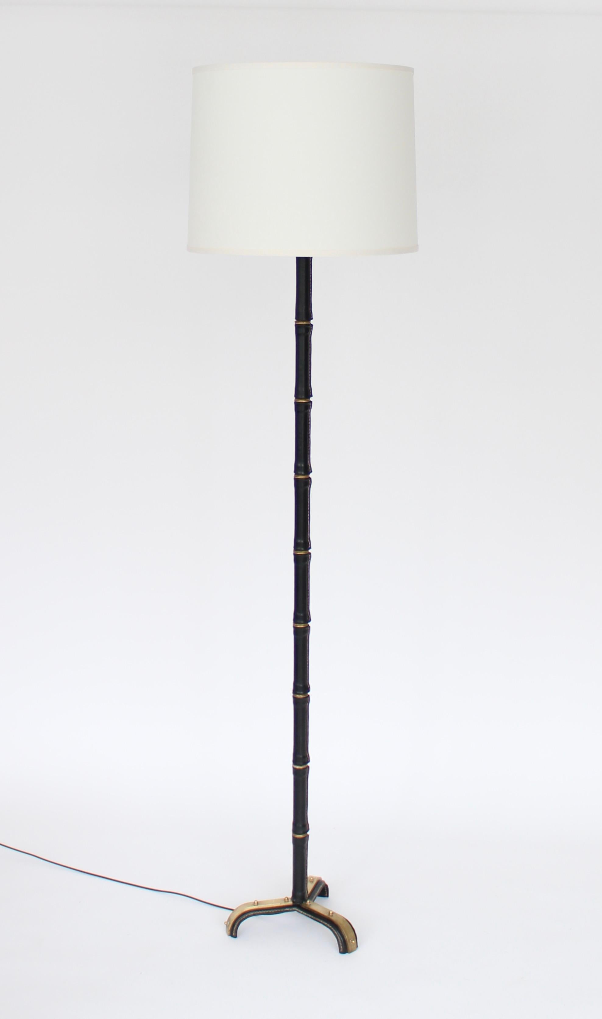 French designer Jacques Adnet leather wrapped floor lamp with signature bamboo leather and brass stem and contrast stitching. Leather all the way down to the tripod base with nice brass details throughout and on the base. 
Newly rewired with new