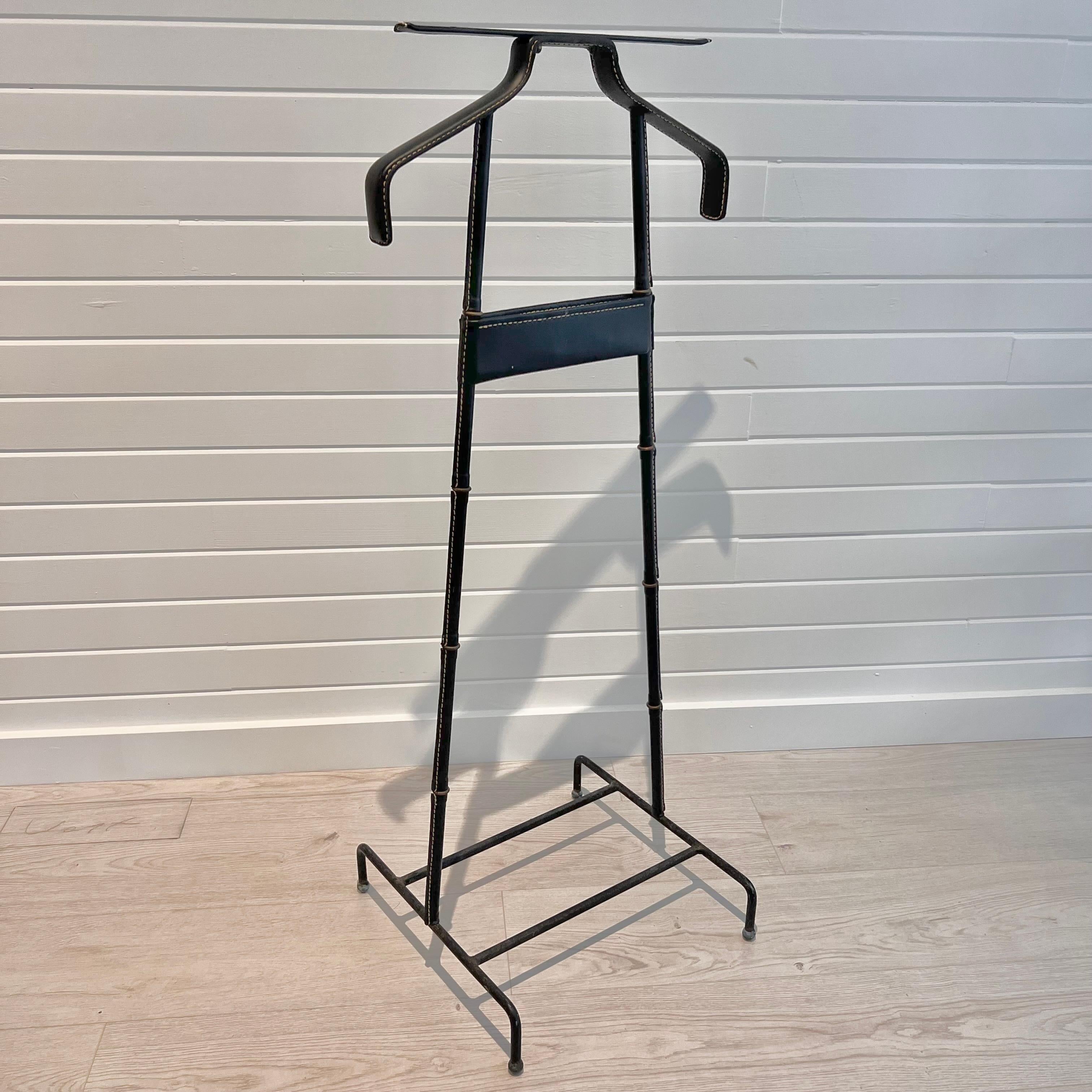 Handsome black coat stand / valet by Jacques Adnet. Valet has a black iron base with brass ball feet giving it an elegant and contrasted brutalist touch. Iron body wrapped in a black leather with brass ring separators giving it the classic Adnet
