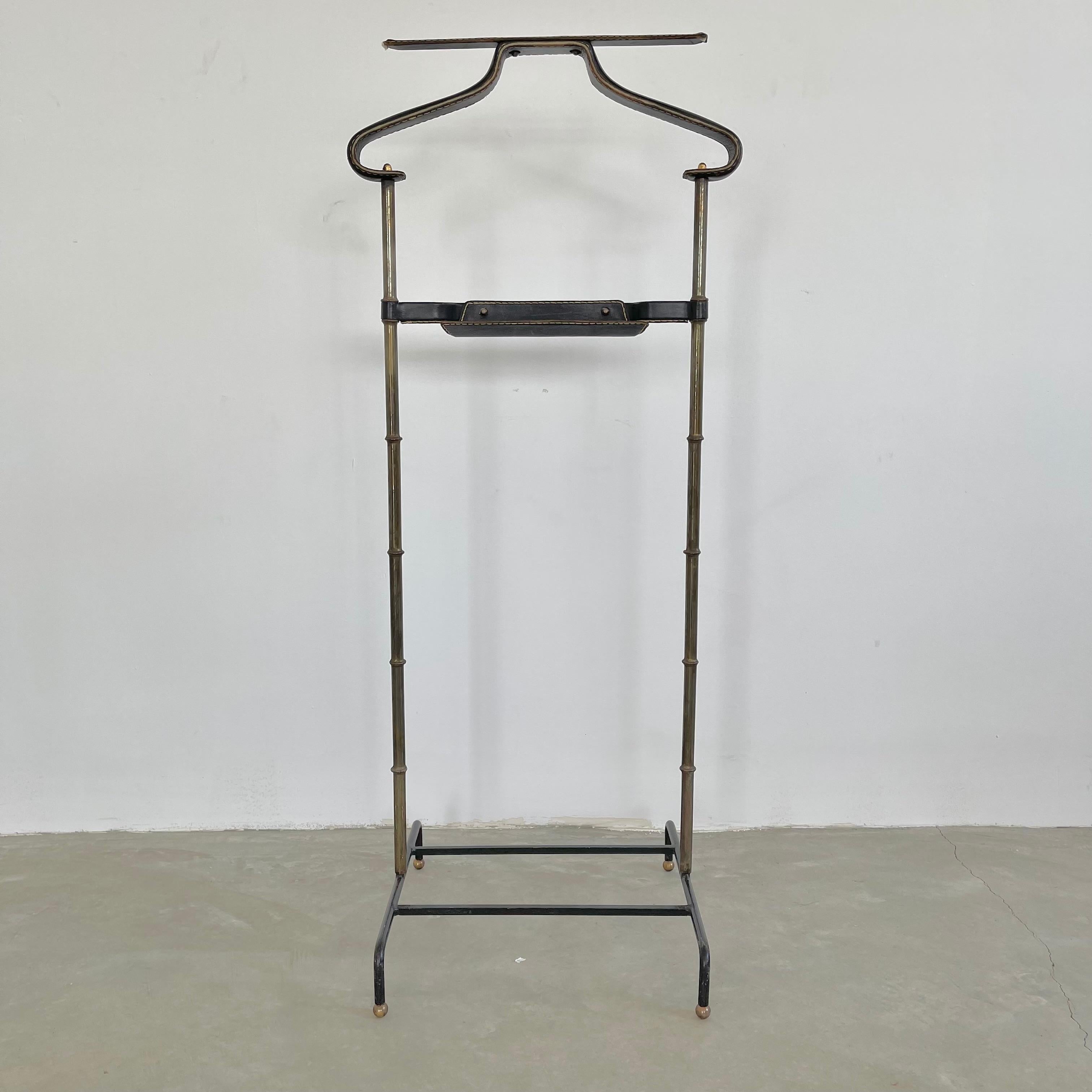 Handsome coat stand / valet by Jacques Adnet. Valet has an iron base, brass frame in a bamboo design and a leather wrapped catch all and coat/pant holder. Leather has signature Adnet contrast stitching. Beautiful vintage condition. Great piece of