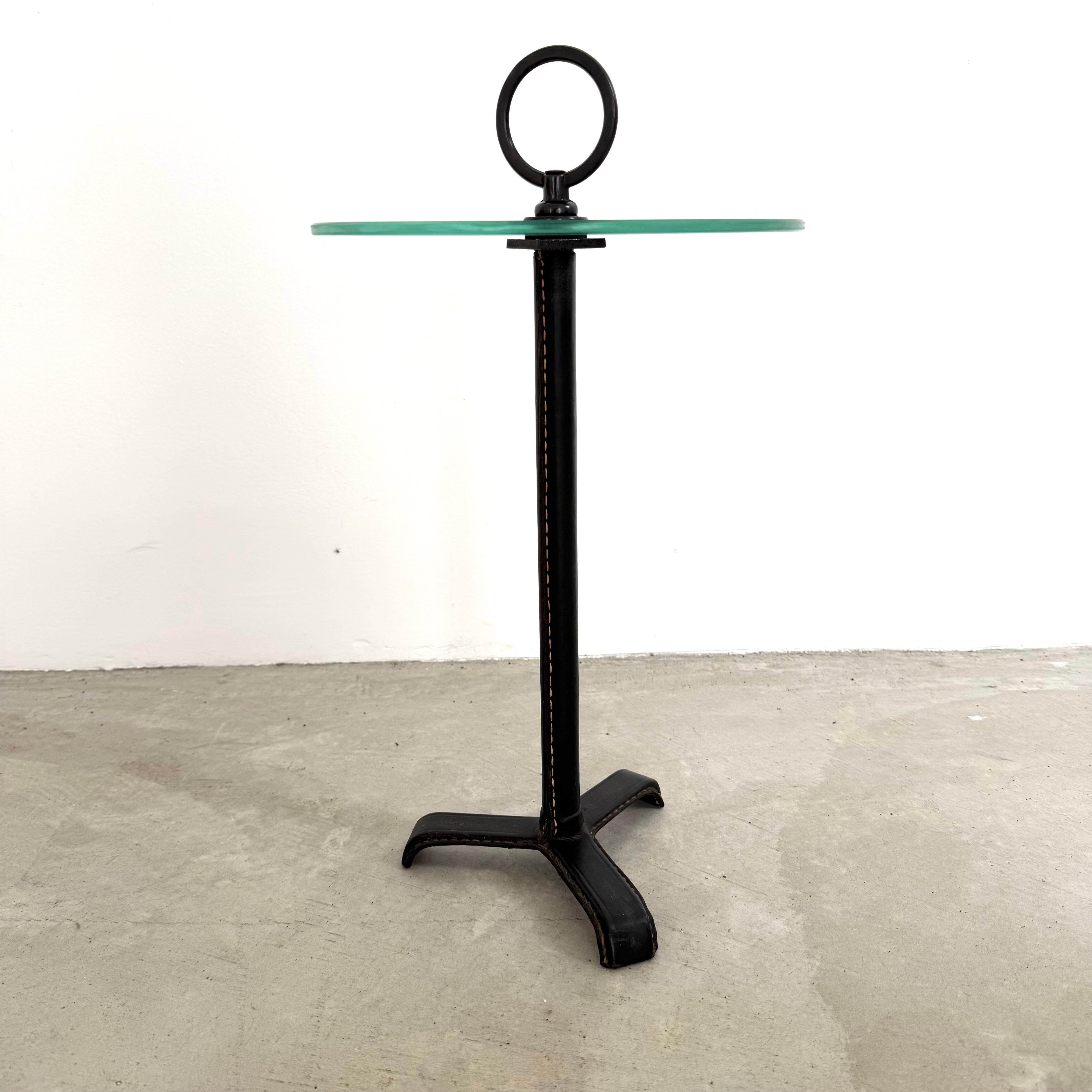 Exceptionnelle table d'appoint en cuir et verre de Jacques Adnet. Magnifique cuir noir avec surpiqûres contrastées. Boucle en laiton antique sur le dessus. Parfait pour les boissons ou comme table d'appoint. Une belle pièce de collection signée