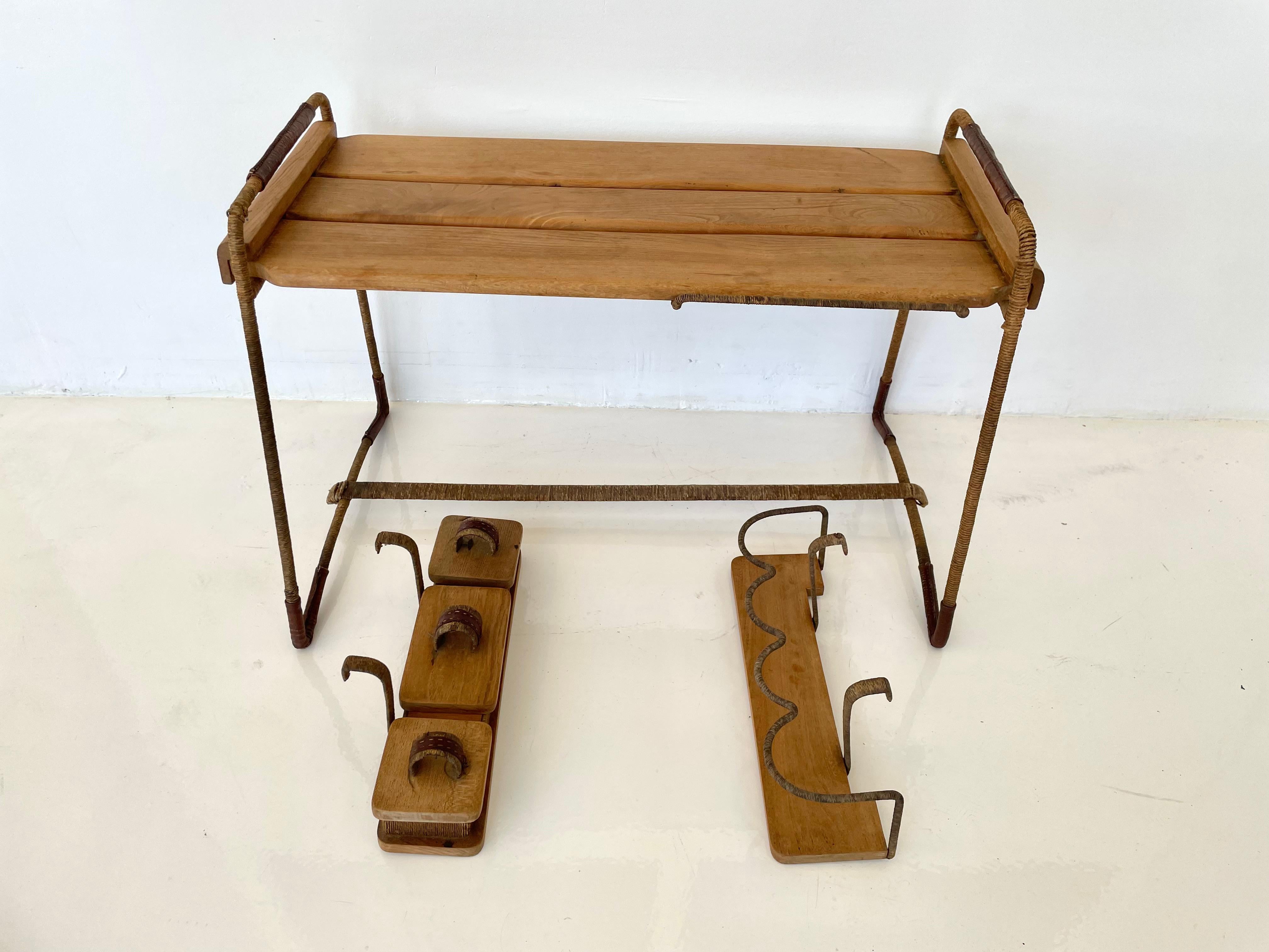 Handsome serving cart by French designer Jacques Adnet. Leather and twine wrapped frame with two removable attachments on the sides. Leather wrapped corners with signature Adnet stitching. One side has a drink caddy that holds three bottles. The
