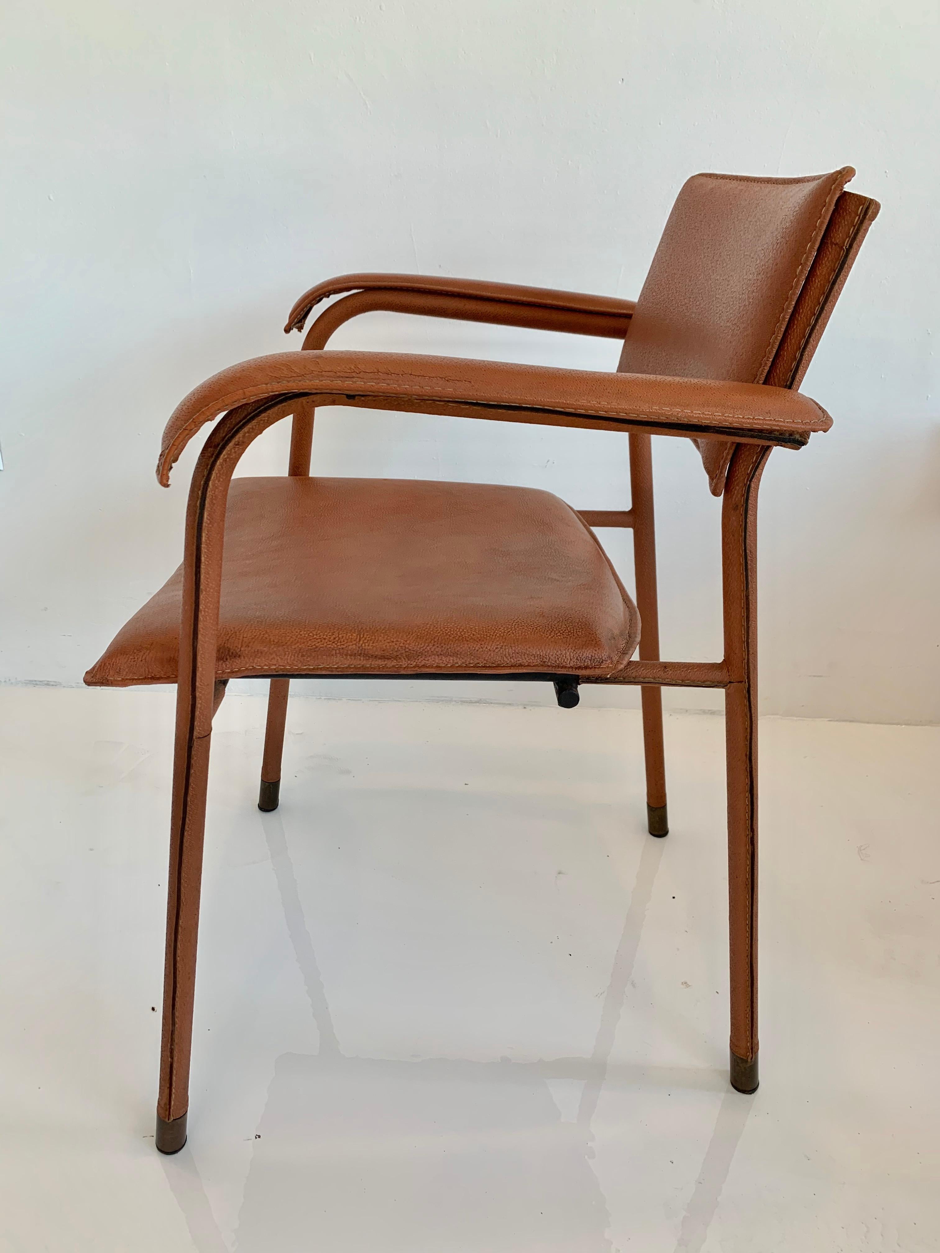 Rare leather and iron armchair by French designer Jacques Adnet. Entire chair is wrapped in handstitched leather. Brass capped feet and brass hardware detailing on chair backs. Seat bottom, seat back, arms, and frame detailing all wrapped in