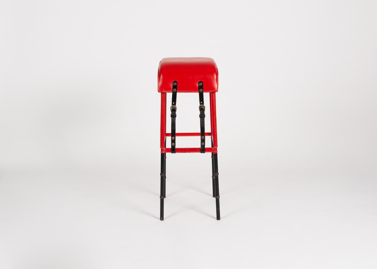 This spare bar stool in leather and painted cast iron sets up a stark contrast between form and composition. Constructed in sleek lines, and of Industrial and semi-Industrial materials, it nevertheless possesses an exuberant coloring and bold