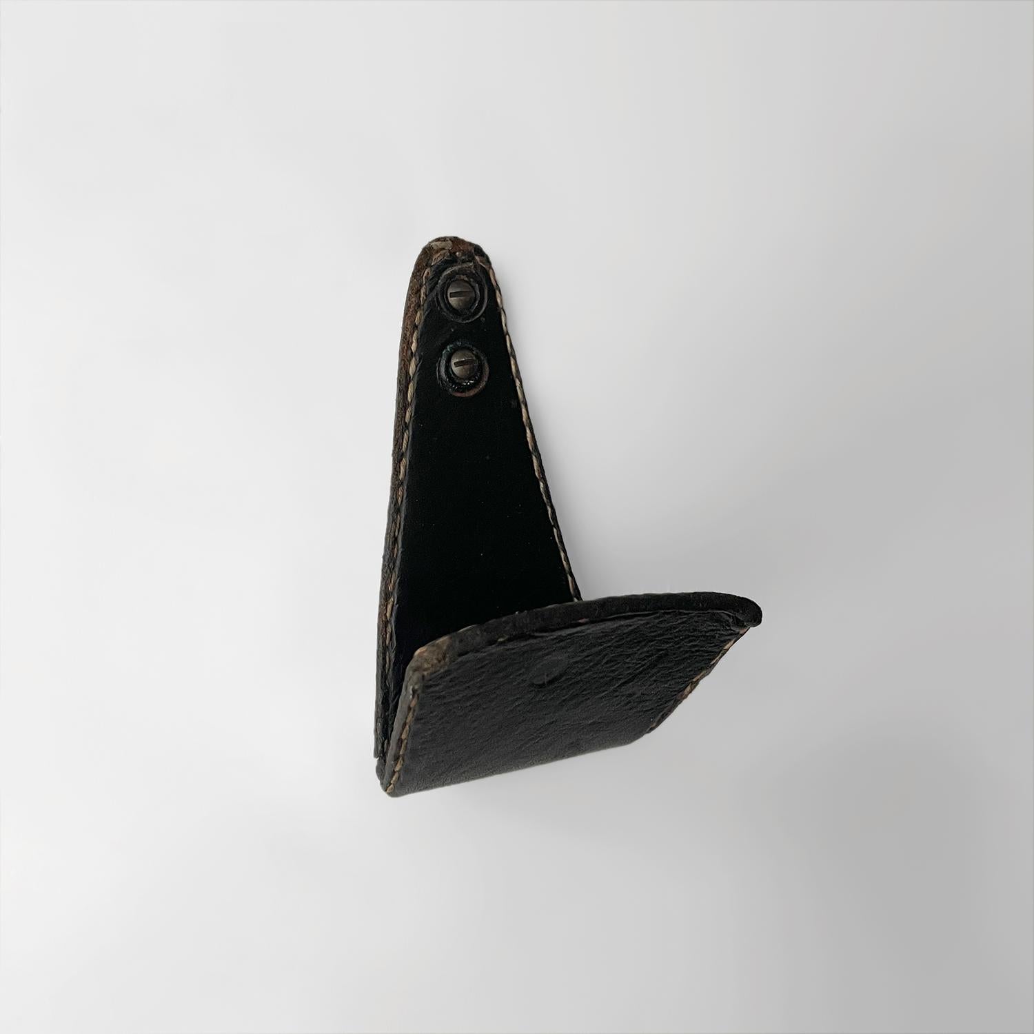 Jacques Adnet Kleiderhaken aus Leder
Frankreich, etwa 1940er Jahre 
Schwarzes Leder mit charakteristischen Kontrastnähten
Leichte Oberflächenmarkierungen 
Patina durch Alter und Gebrauch - siehe Fotos
