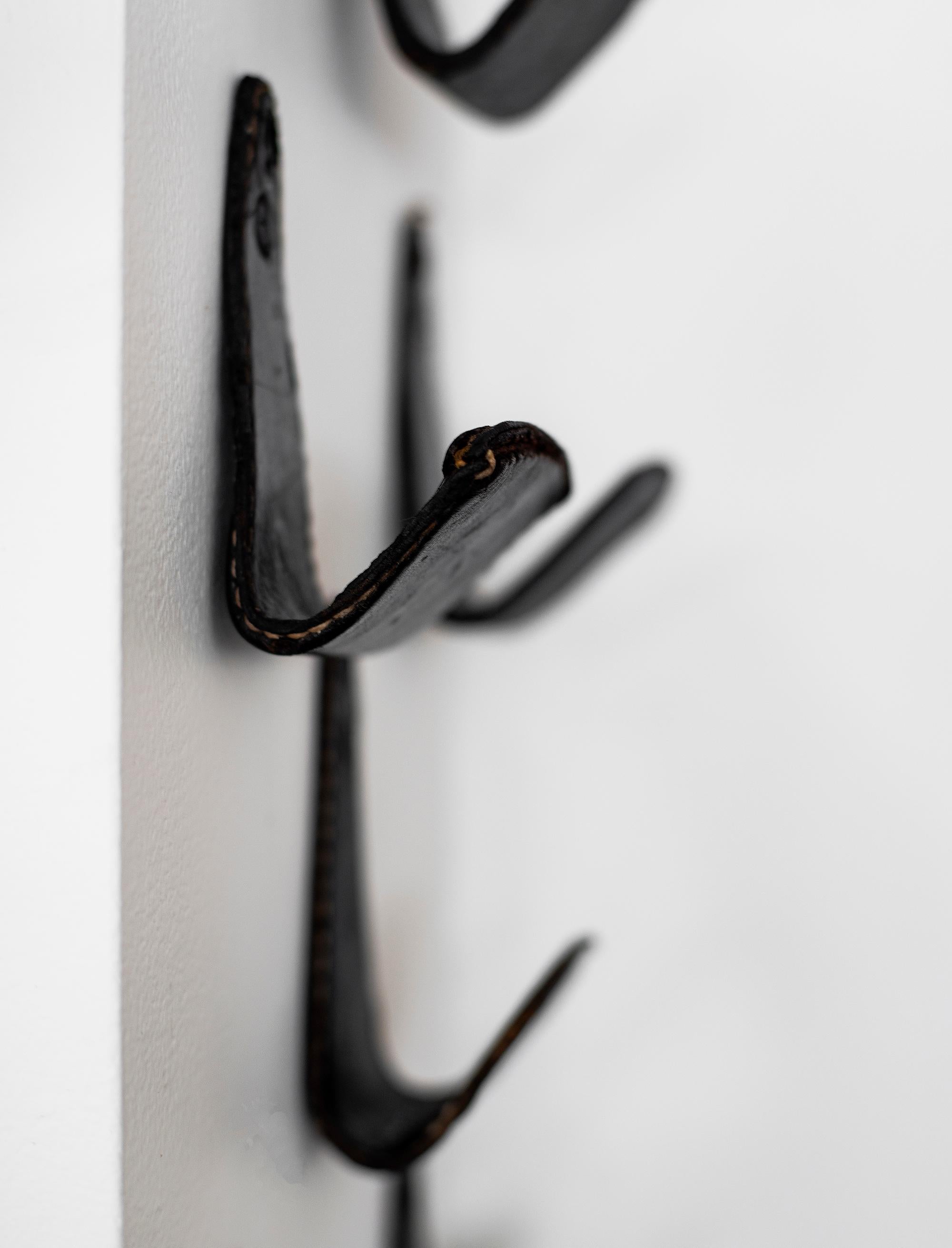Stunning Jacques Adnet attributed coat hook. Original black leather with white contrast stitching. 1 available. 