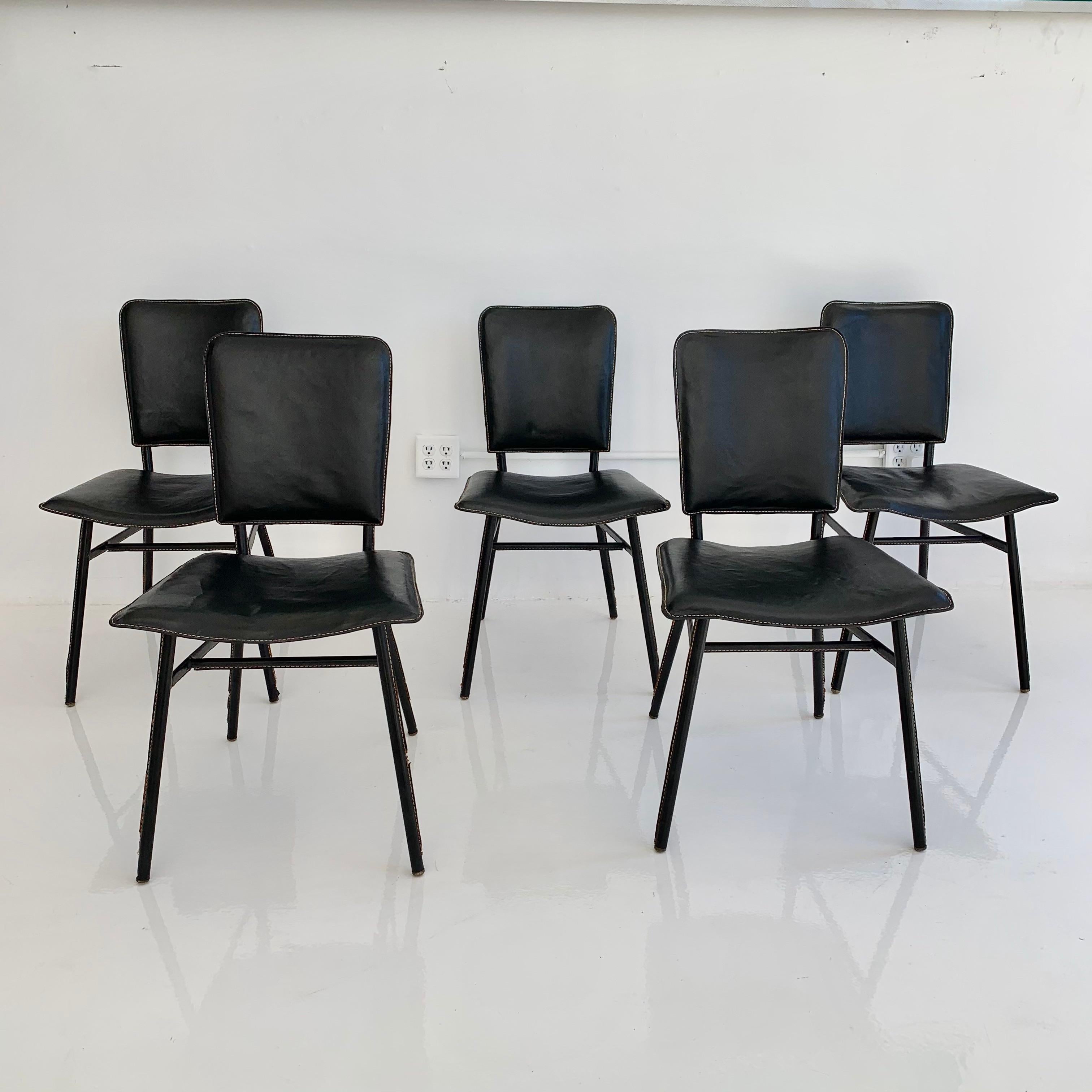 Exquisite dining table and chairs by French designer Jacques Adnet. Every piece of the table and chairs is covered in black leather. Extremely collectible set. Signature Adnet contrast stitching throughout. Very good condition. Sold as a set. Set
