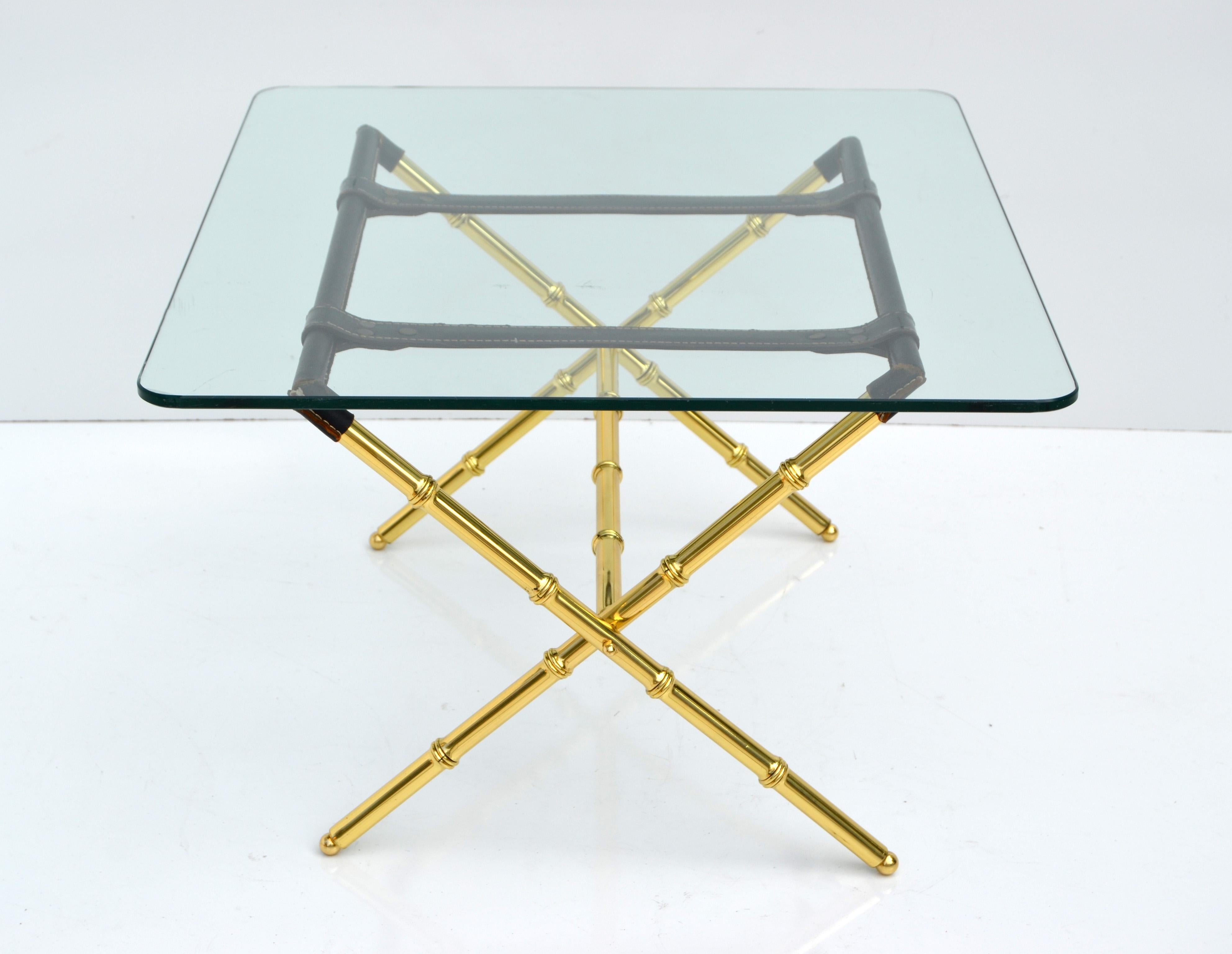 Superbe table basse en verre de Jacques Adnet, avec une base en X en laiton poli et plié, en faux bambou avec des reliures en cuir cousues à la main.
Le plateau en verre rectangulaire a des bords arrondis et son épaisseur est de 0,38 pouce.
La