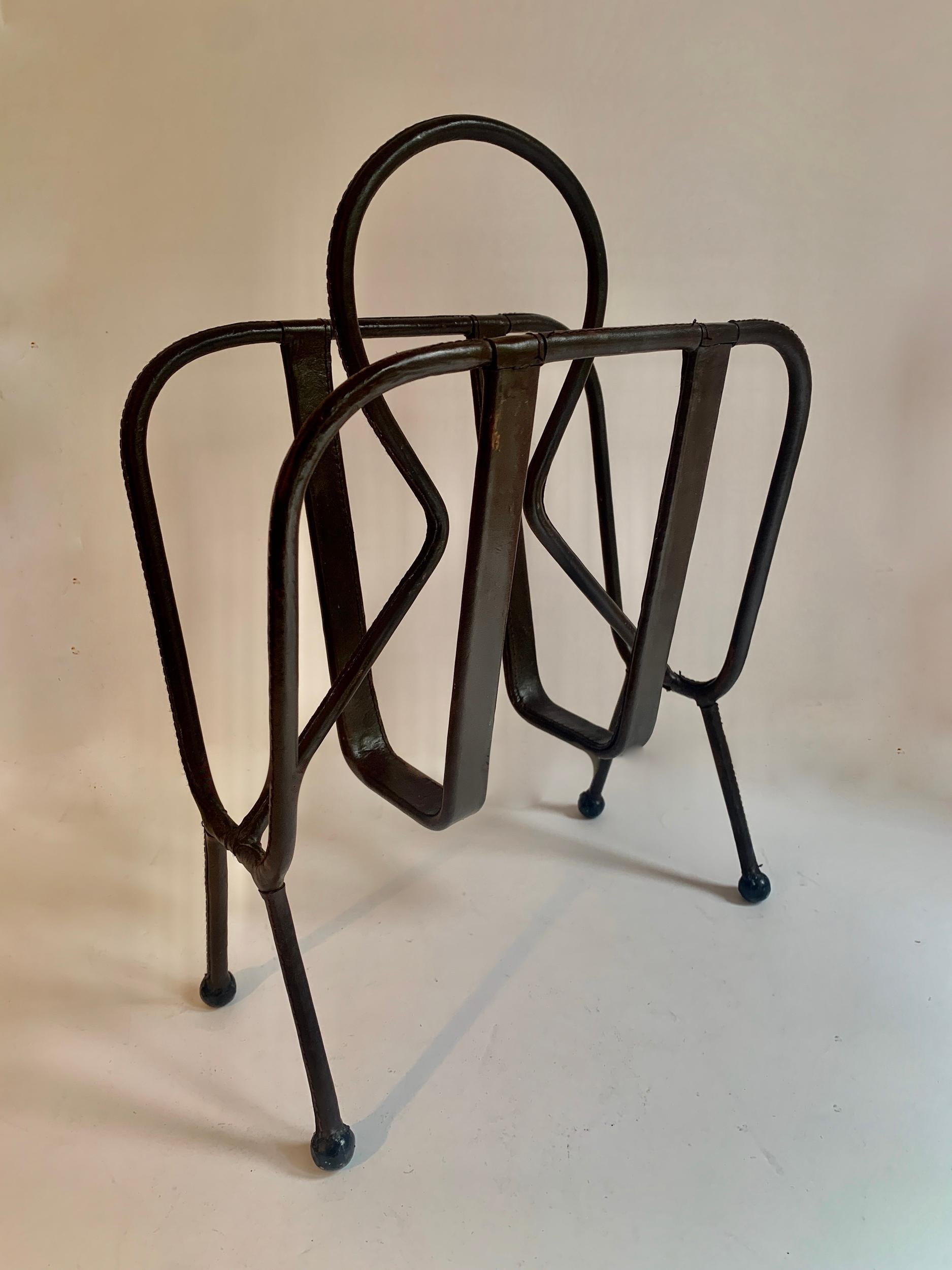 French designer Jacques Adnet is best known for impeccable designs that bring leather, function and design together. 

The magazine rack with iron structure in wonderful condition for the age, is stitched with perfection. The design is