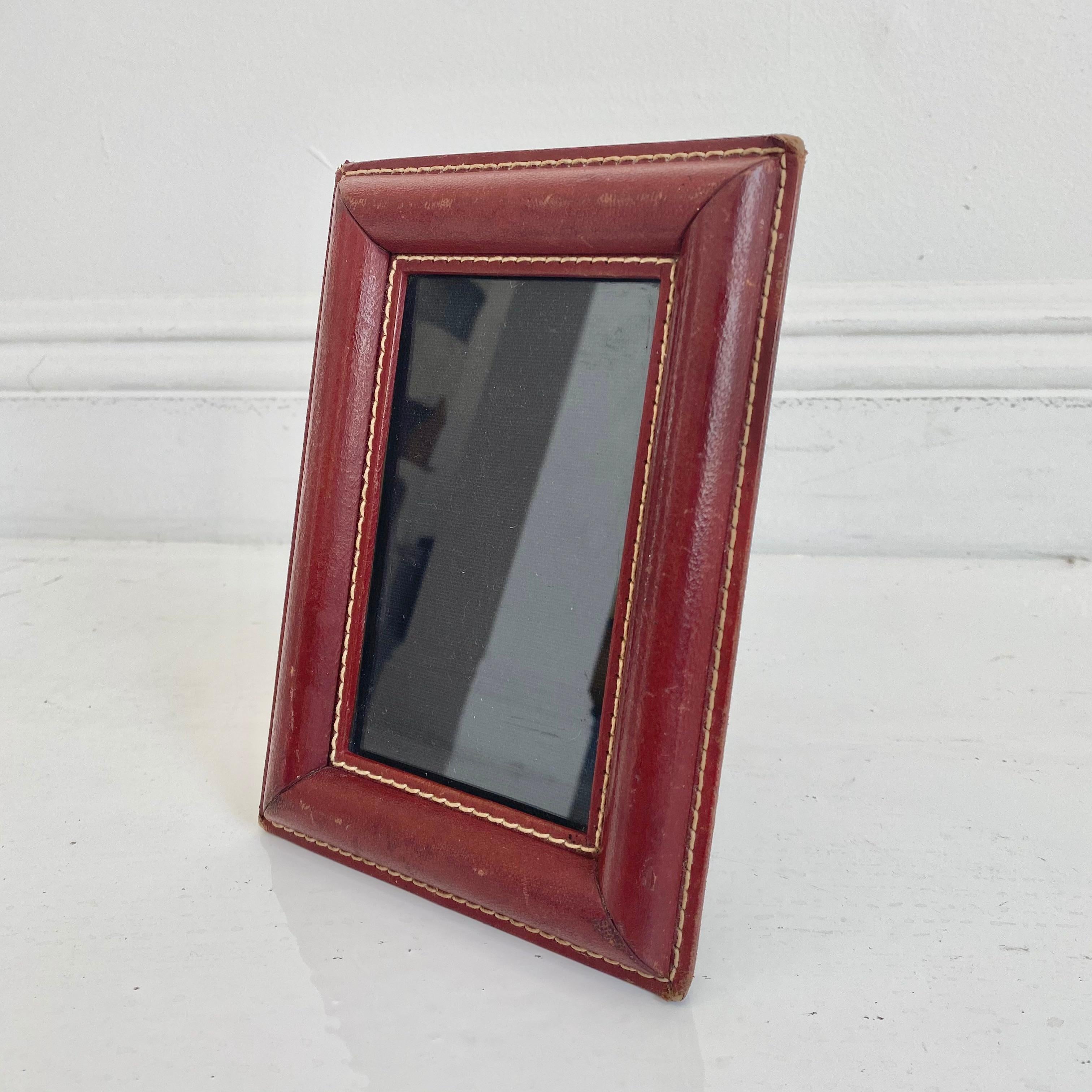 Handsome French leather picture frame by Jacques Adnet. Red leather with signature Adnet contrast stitching. Very good vintage condition. Great patina and age to leather.