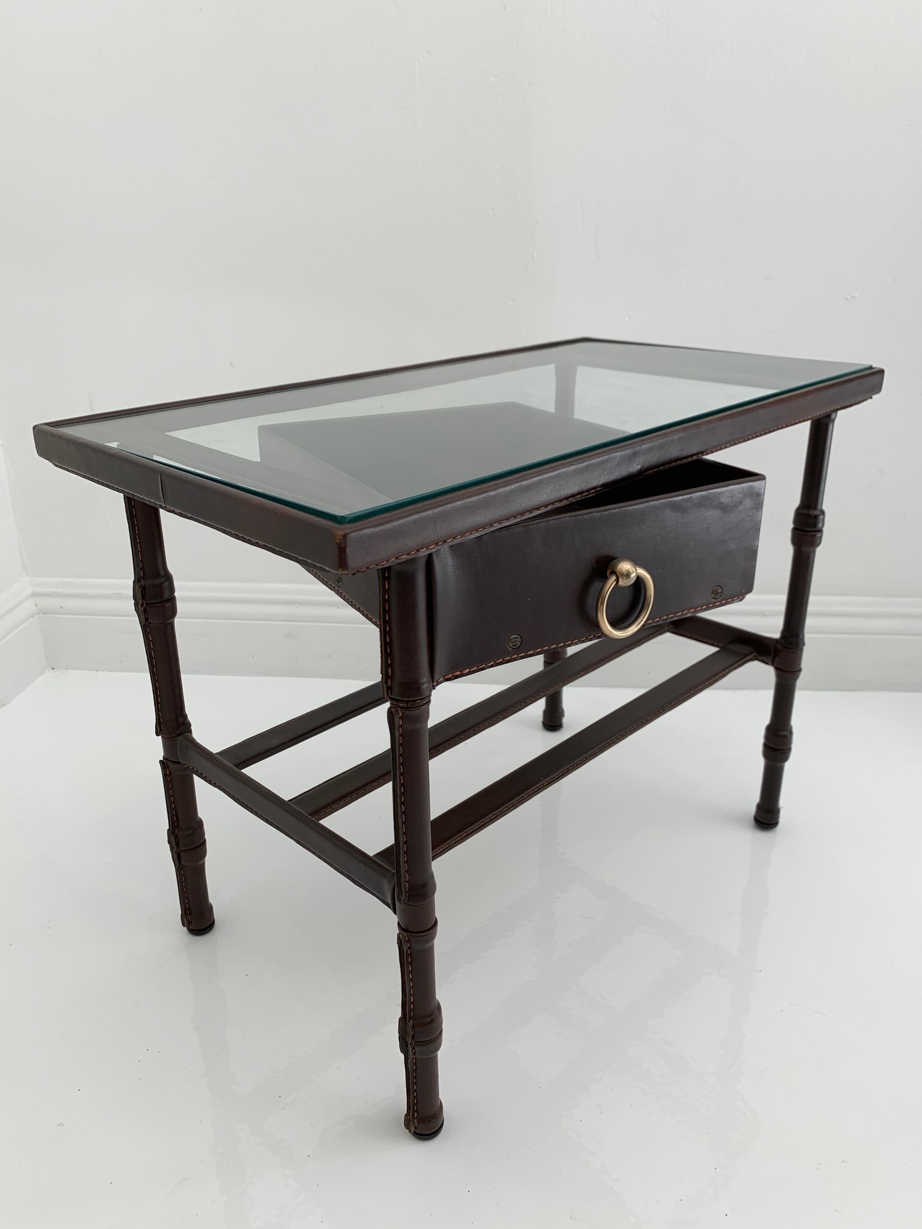 Jacques Adnet leather side table with glass top and swivel drawer. The entire table is wrapped in chocolate brown leather with signature Adnet contrast stitching. Drawer swivels easily 180 degrees away from table and then tucks in perfectly once