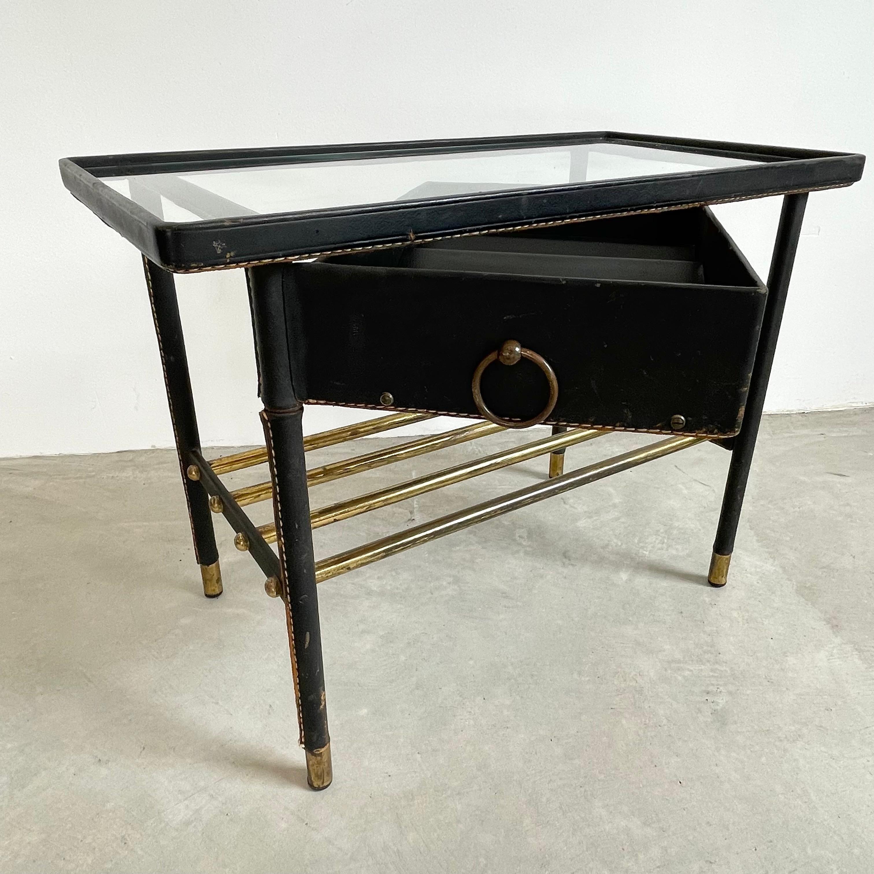 Jacques Adnet leather side table with glass top and swivel drawer. The entire table is wrapped in black leather with signature Adnet contrast stitching. Drawer swivels easily 180 degrees away from table and then tucks in perfectly once closed under