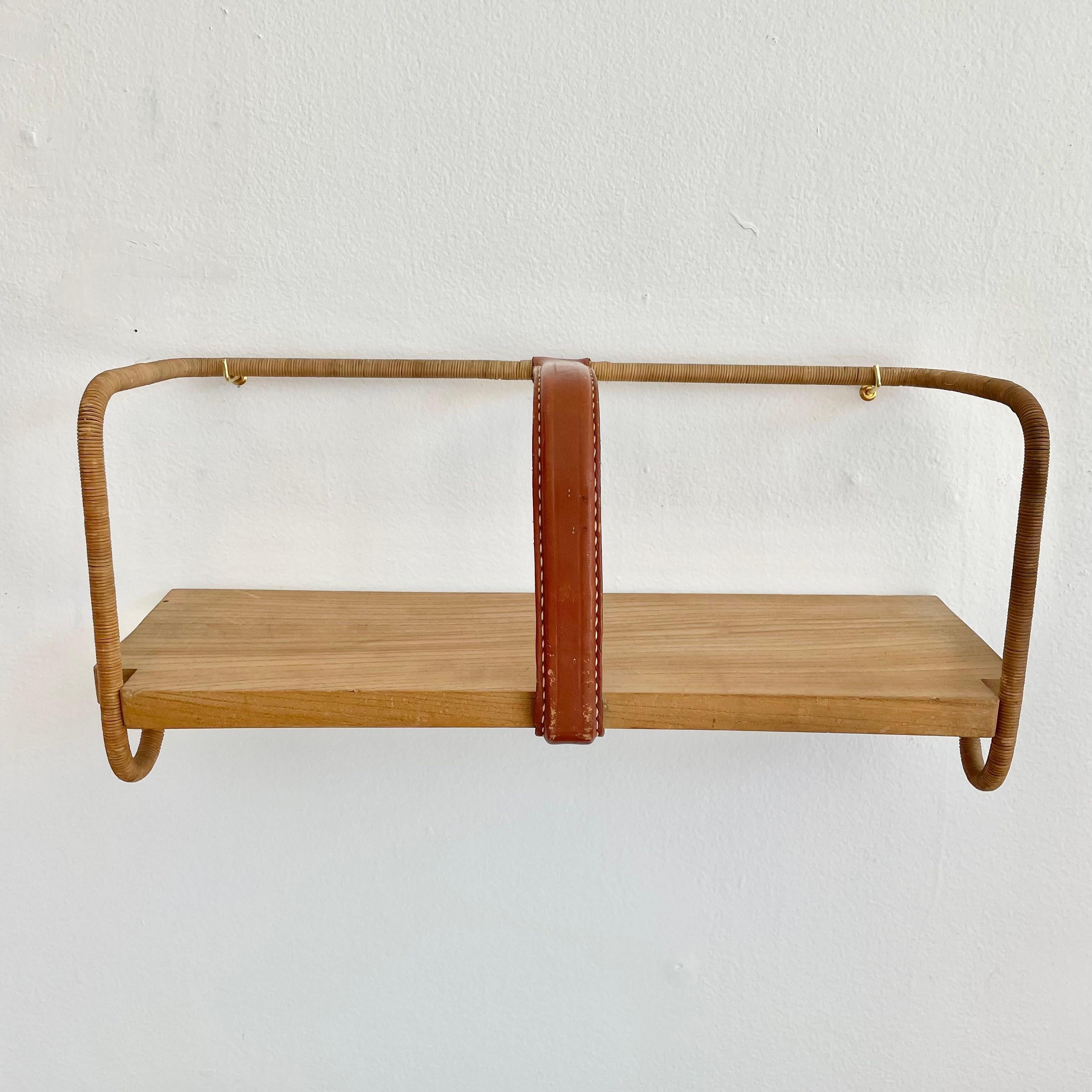 Sculptural shelf by French modernist designer, Jacques Adnet. A simple yet elegant design with a thick wooden shelf held together by a metal frame. Leather divider right in the middle with signature Adnet contrast stitching. Metal completely wrapped