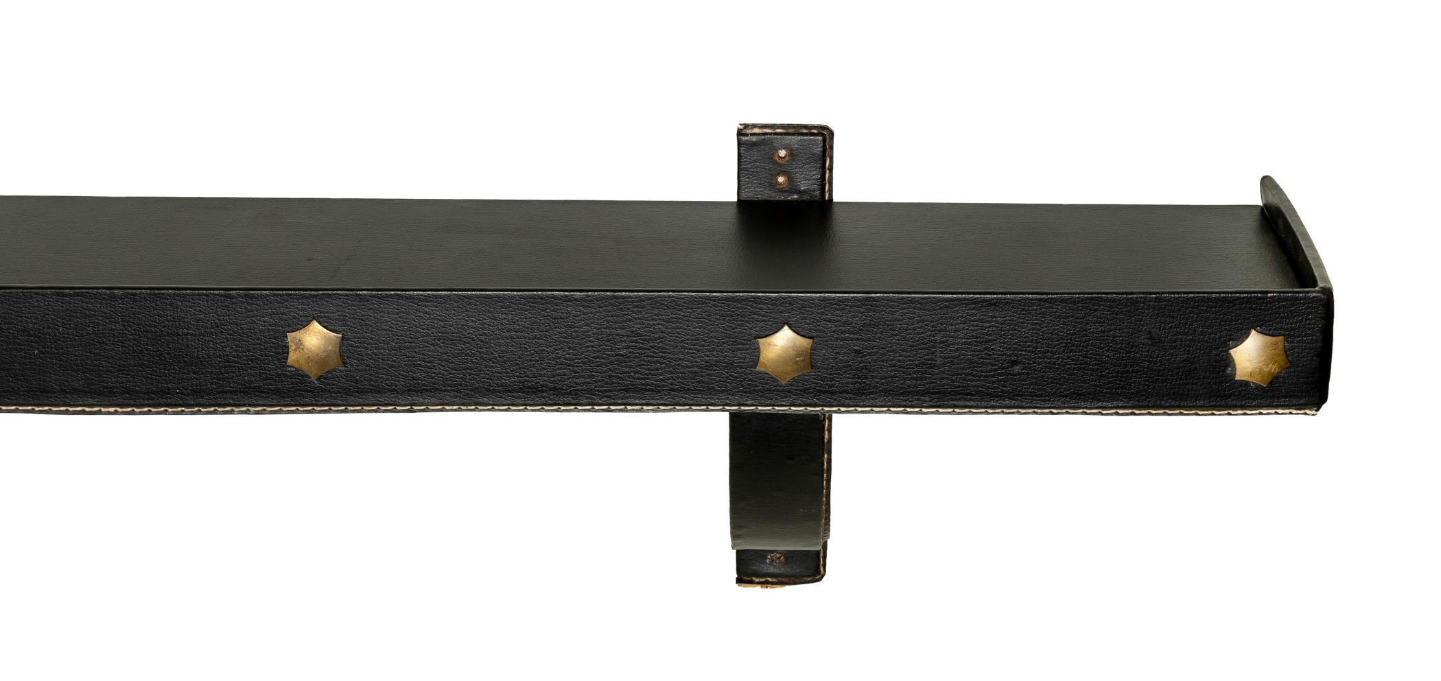 A fantastic leather clad wall shelf with brass accents.