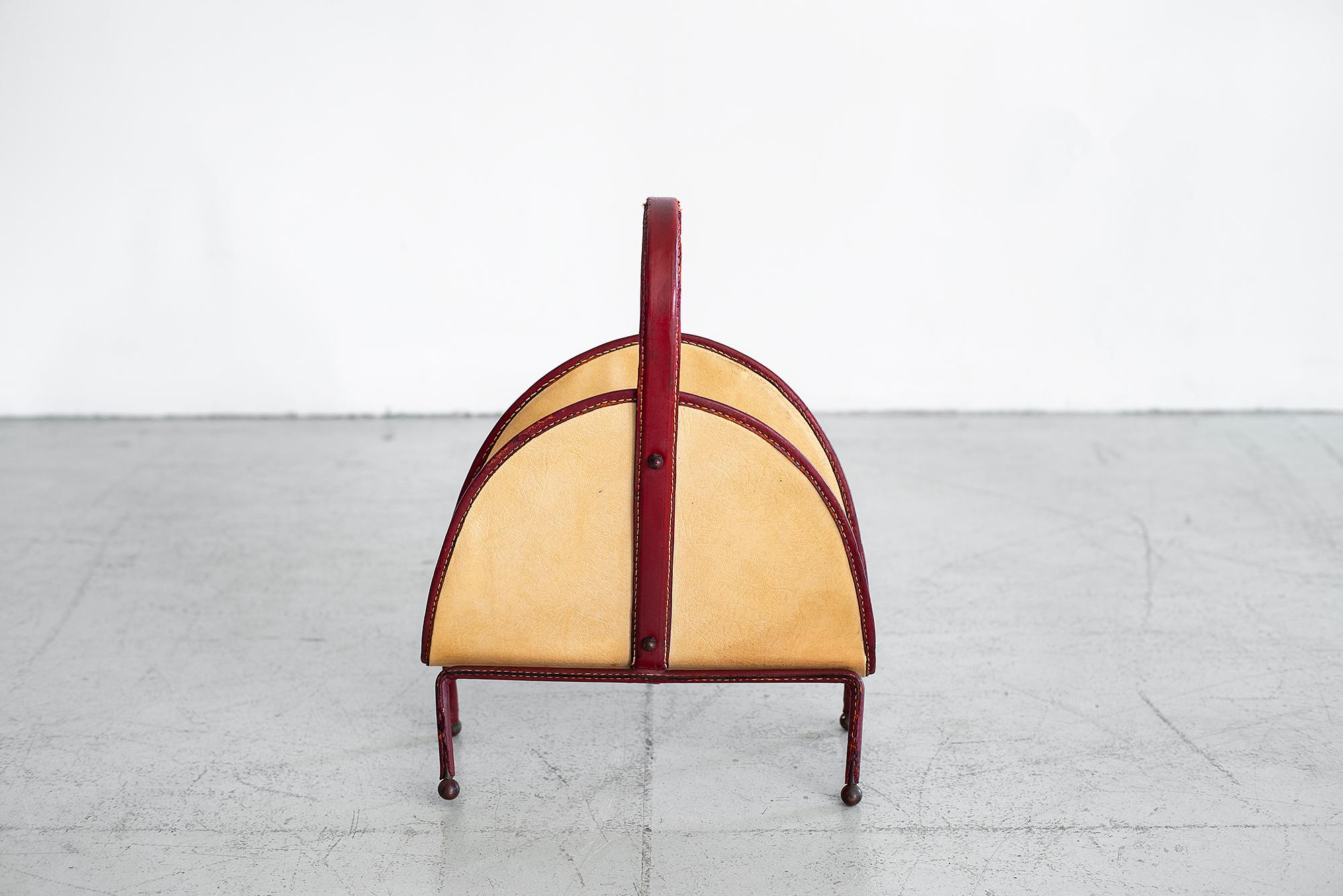 Rare Jacques Adnet magazine rack with tan and red leather, contrast stitching and brass ball tip feet. Beautiful, unique piece.
Some wear and crack in leather on leg.