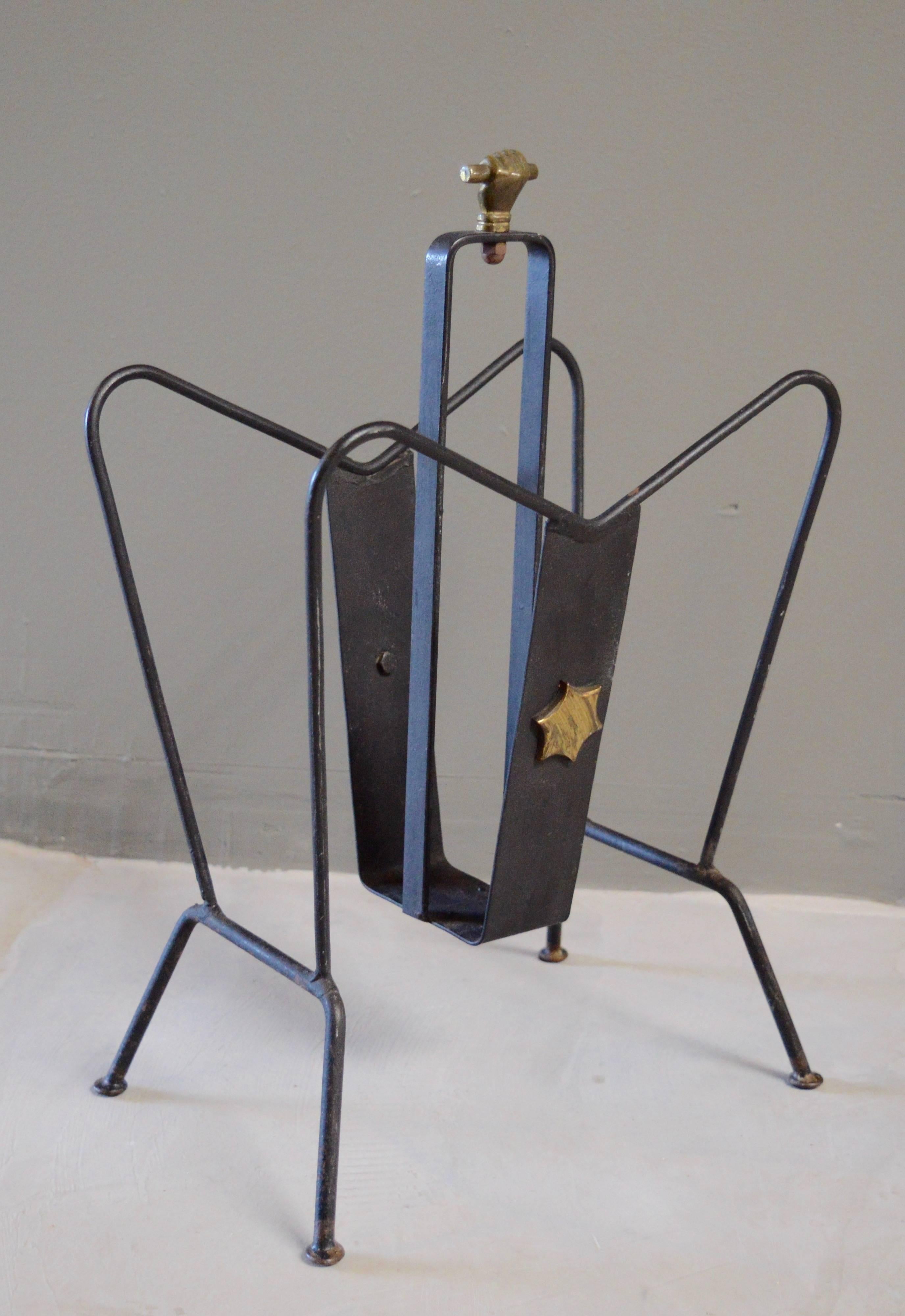 Handsome magazine rack by Jacques Adnet. Made of iron and brass. Excellent vintage condition. Star detail on both sides and closed fist on top. Great piece!