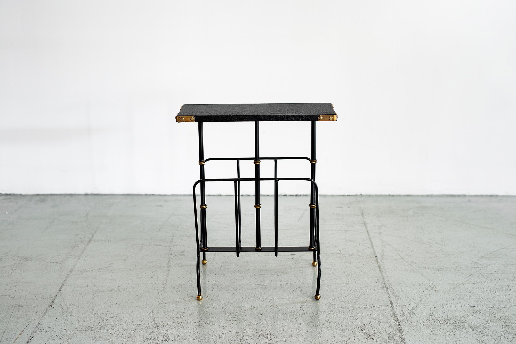 Jacques Adnet magazine table with magazine rack. 
Black leather top, signature brass and black bamboo legs, with iron frame and brass corner detail.