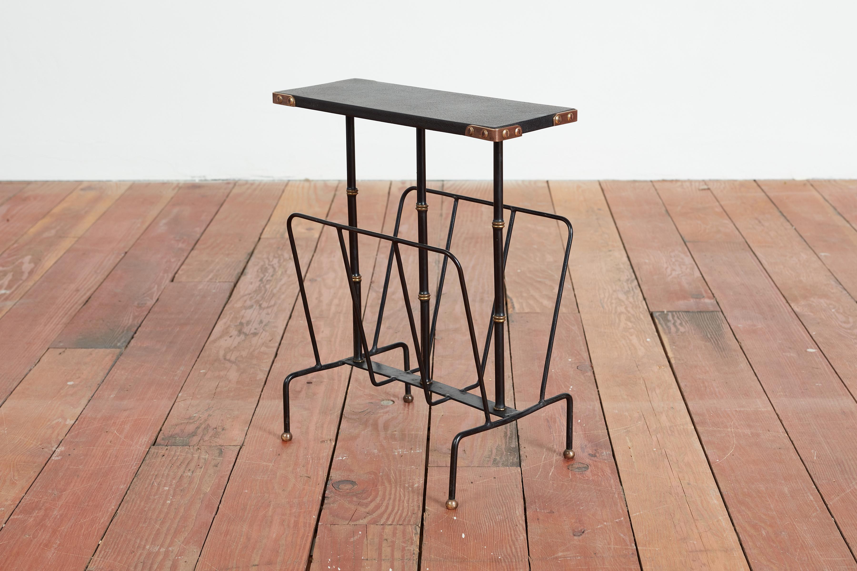 Table à revues avec porte-revues Jacques Adnet. 
Plateau en skaï noir, pieds en bambou noir et laiton, cadre en fer et détails d'angle en laiton.