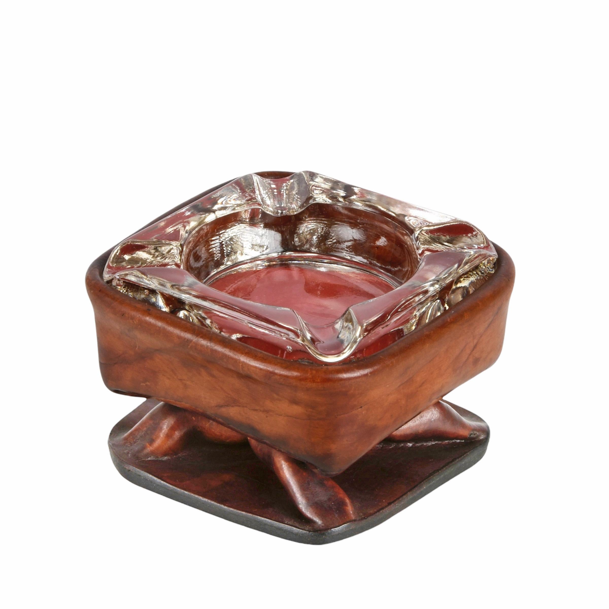 Superb ashtray with a leather body and glass top. This fantastic item is attributed to Jacques Adnet and was produced in France during the 1950s.

The unique element of this magnificent piece is the shape of the leather structure, similar to a
