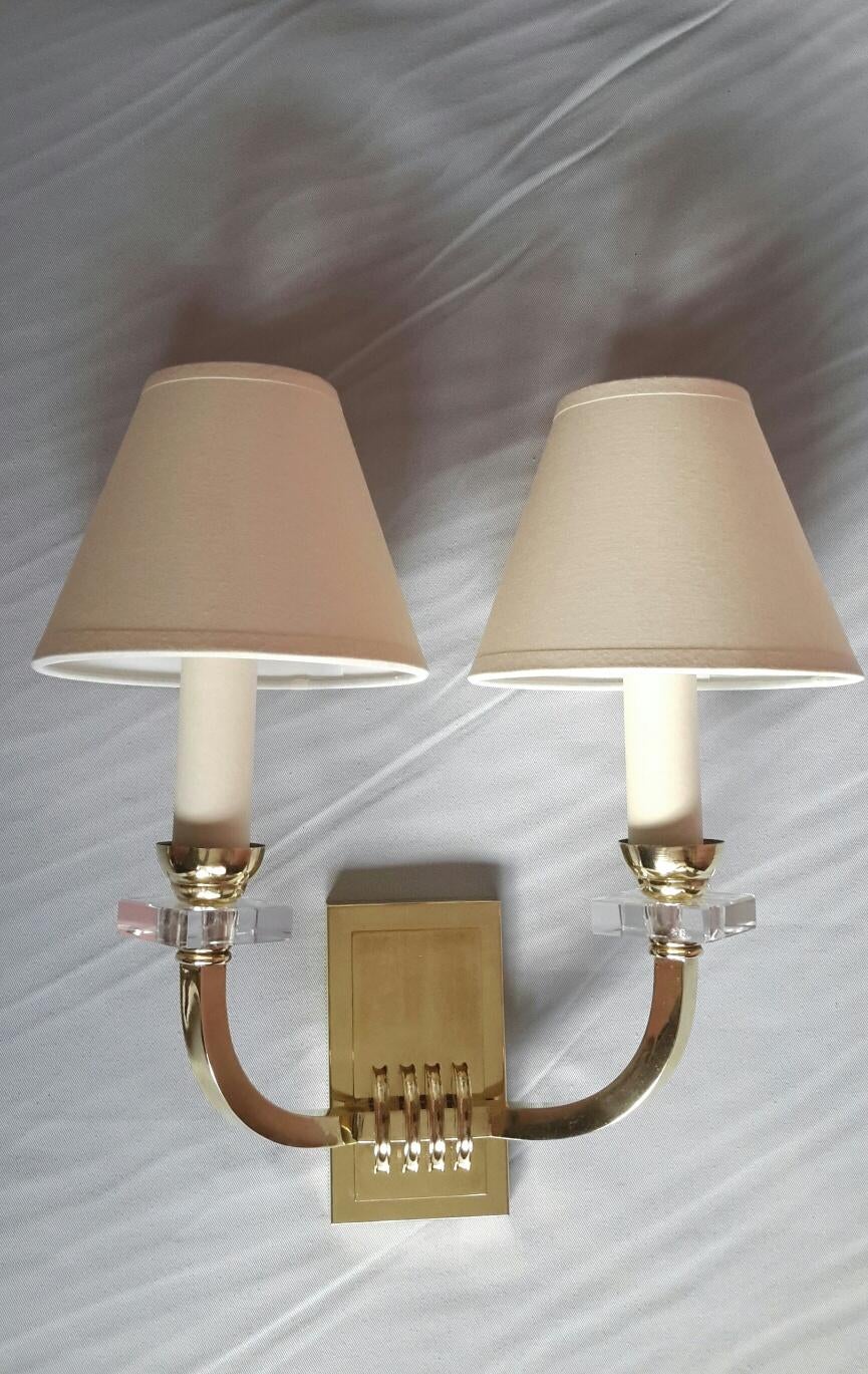 Very elegant pair of gilded bronze, brass and glass double arm wall sconces in the French neoclassical style of the 1950s by Jacques Adnet.
The sconces are in excellent good condition, new rewired and suitable for US standards. They come with new