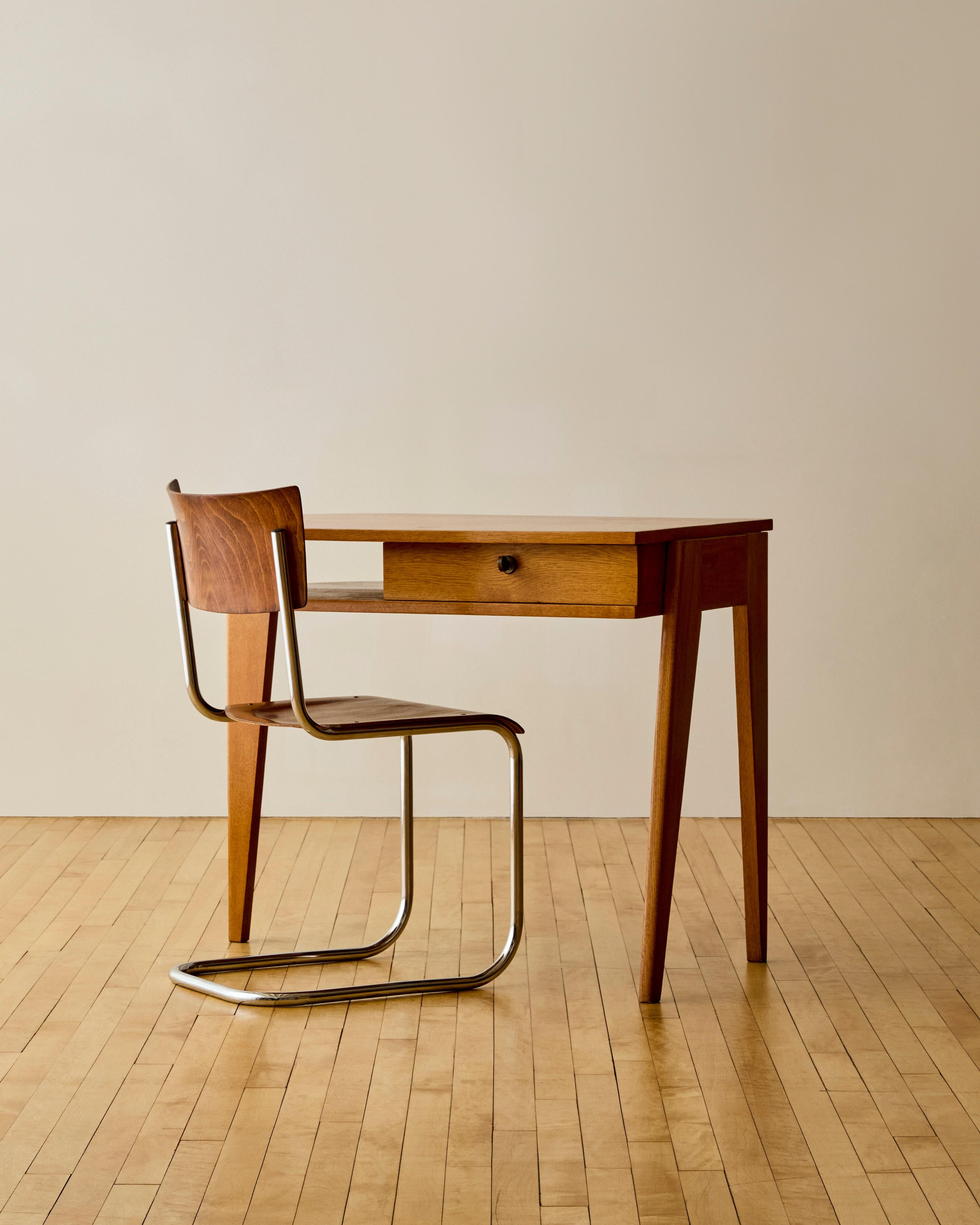 Scrivania a treppiede in Oak dell'architetto modernista francese Jacques Adnet, anni '50 circa. Questa scrivania è dotata di un cassetto scorrevole con meccanismo di chiusura e chiave in ottone abbinata.

Jacques Adnet (1900-1984) è stato un