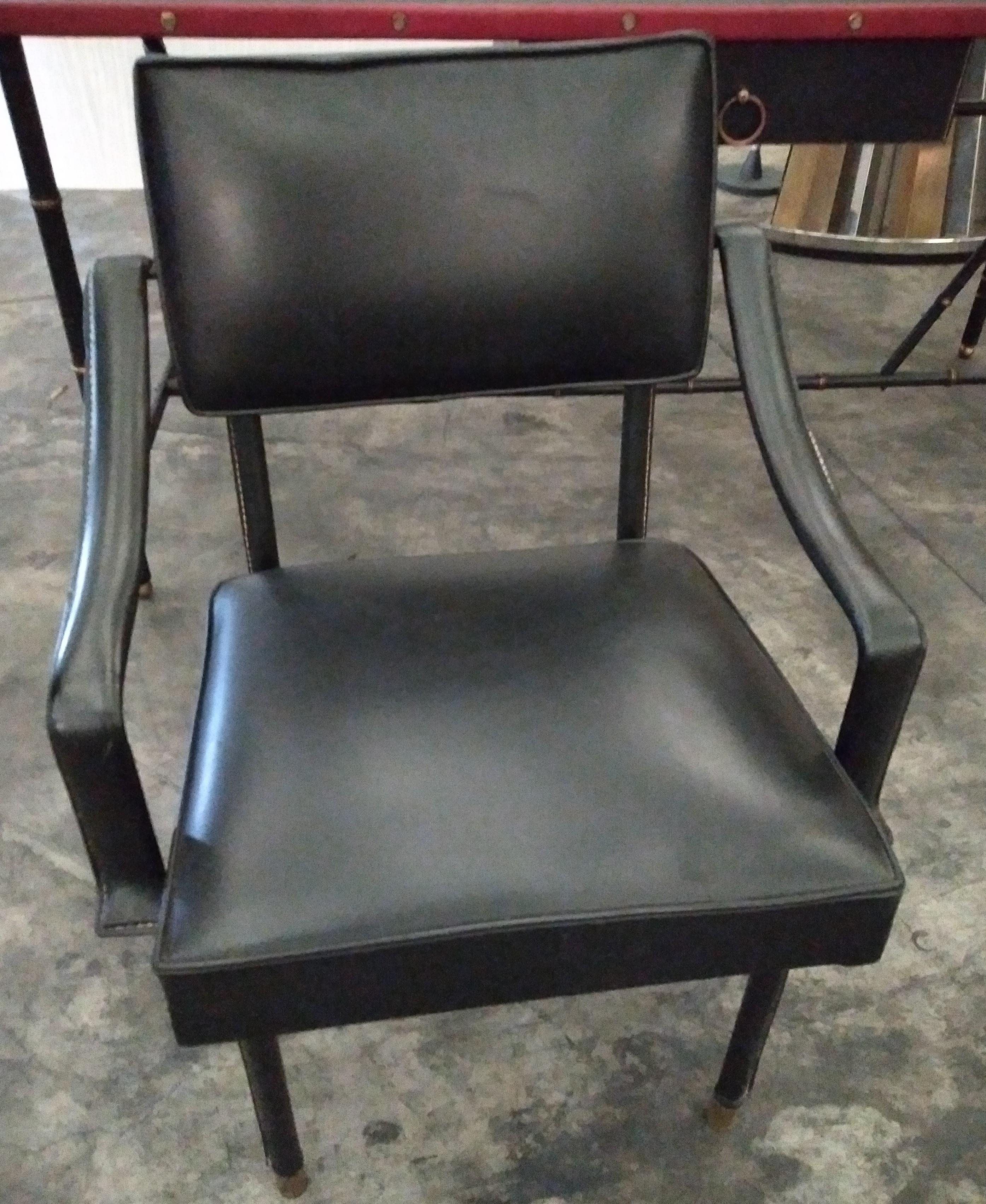 A pair of black leather armchairs designed by Jacques Adnet in France in 1950s.
The metal structure is fully covered in saddle stitched leather. It rests on four gilt bronze feet. 
It can be installed as an office chair or a second is available to