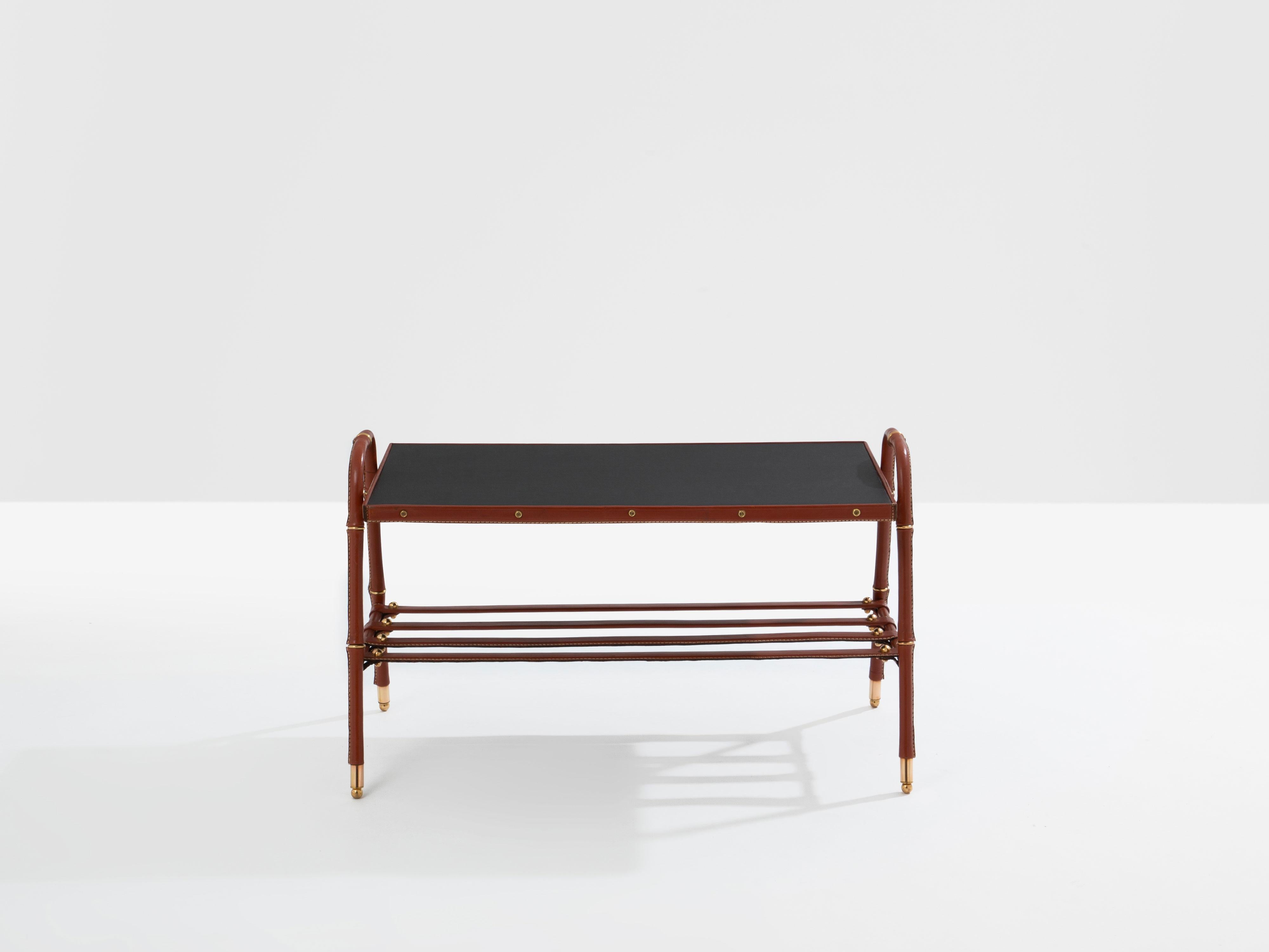 Beautiful coffee table in red leather with black leather top by Jacques Adnet dating from the early 1950s. This coffee table is characteristic of Adnet's work, soft saddle-stitched leather, dit piqué sellier, and visible brass details and screws.