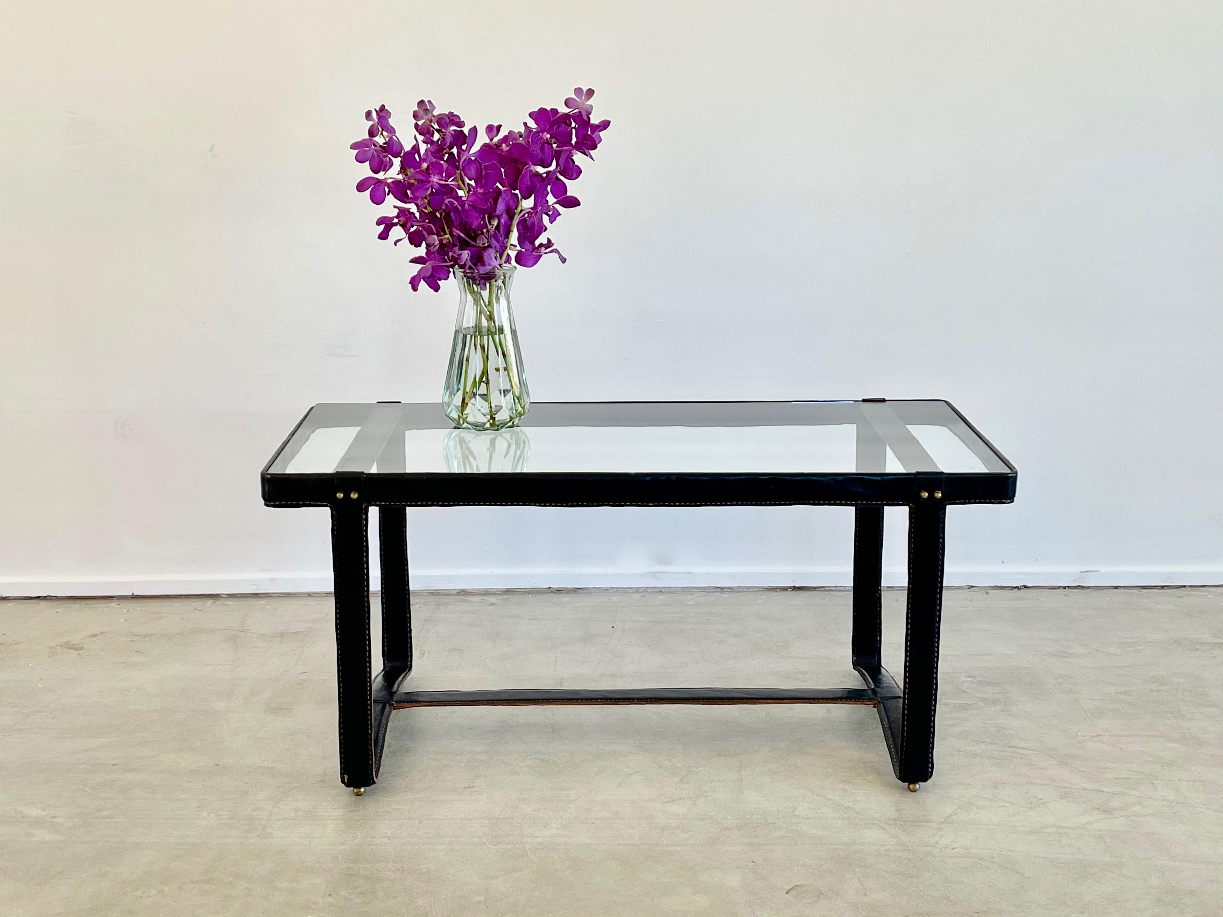 Jacques Adnet rectangular coffee table with signature leather stitching, curved base and brass detailing
New glass top.