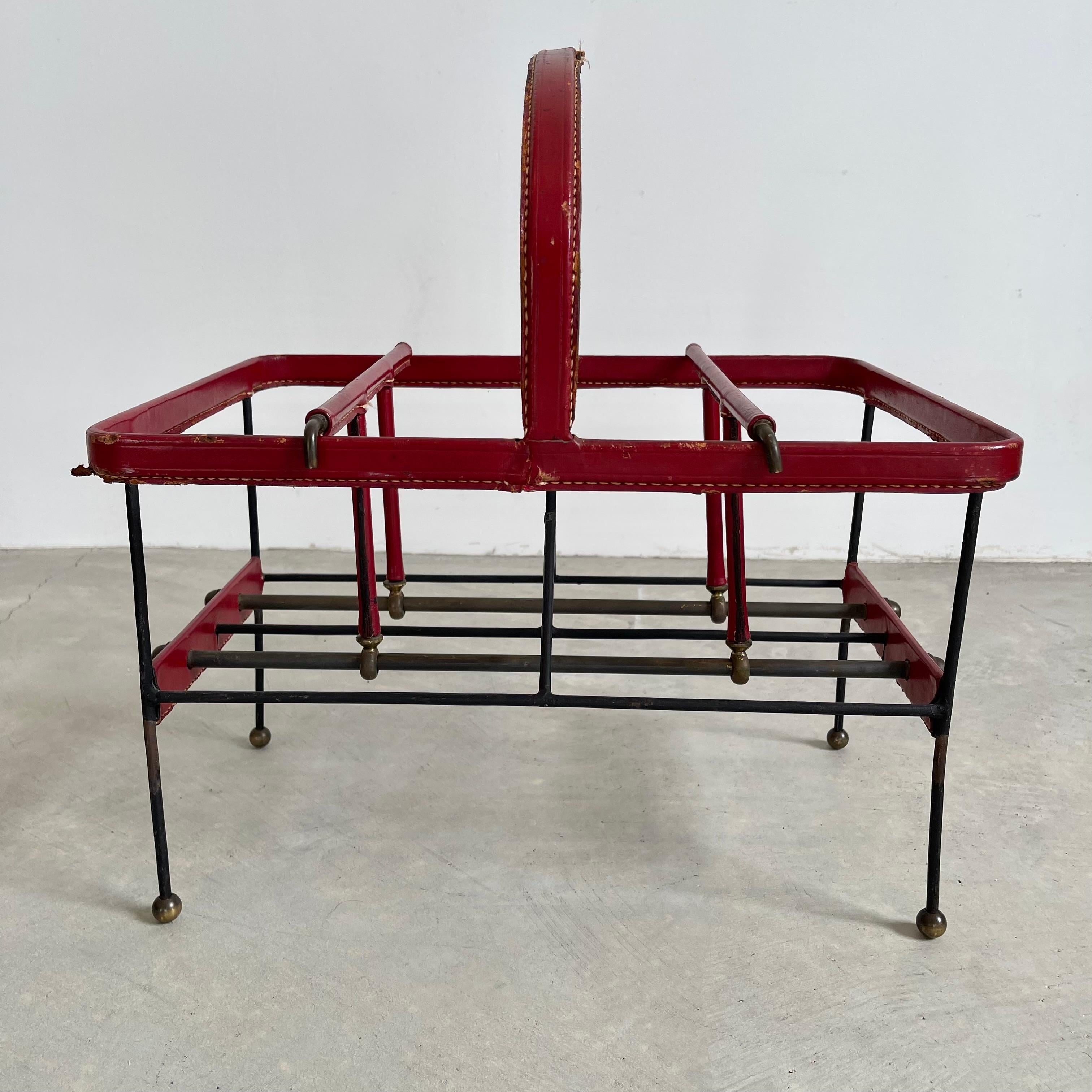Fantastic leather and metal magazine rack by French designer Jacques Adnet. Thick red leather accents on a metal wire frame with brass ball feet. Perfect piece for storing books or magazines. Basket features adjustable dividers on either side of the