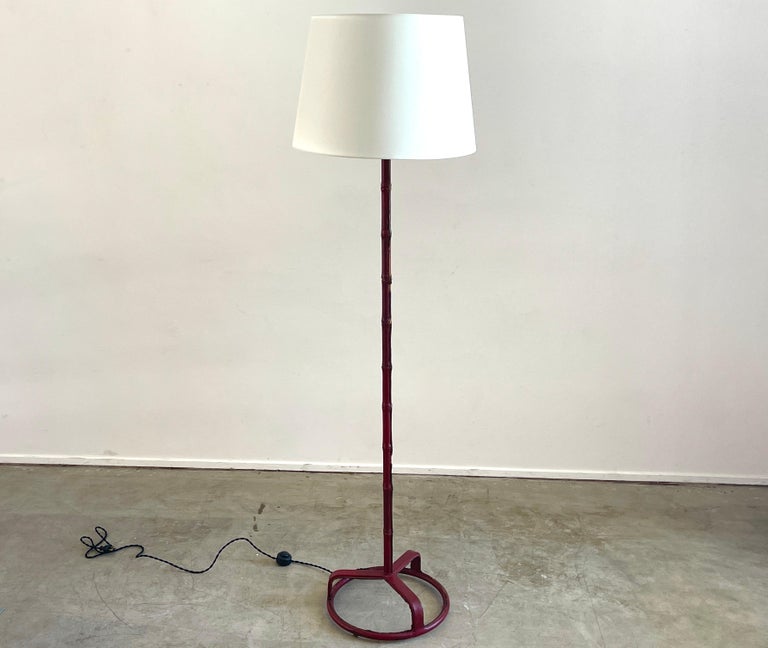 Rare floor lamp by Jacques Adnet in cranberry red leather with signature bamboo stem and circular base. Wonderful example of Adnet. 
Newly rewired and new silk shade.
 