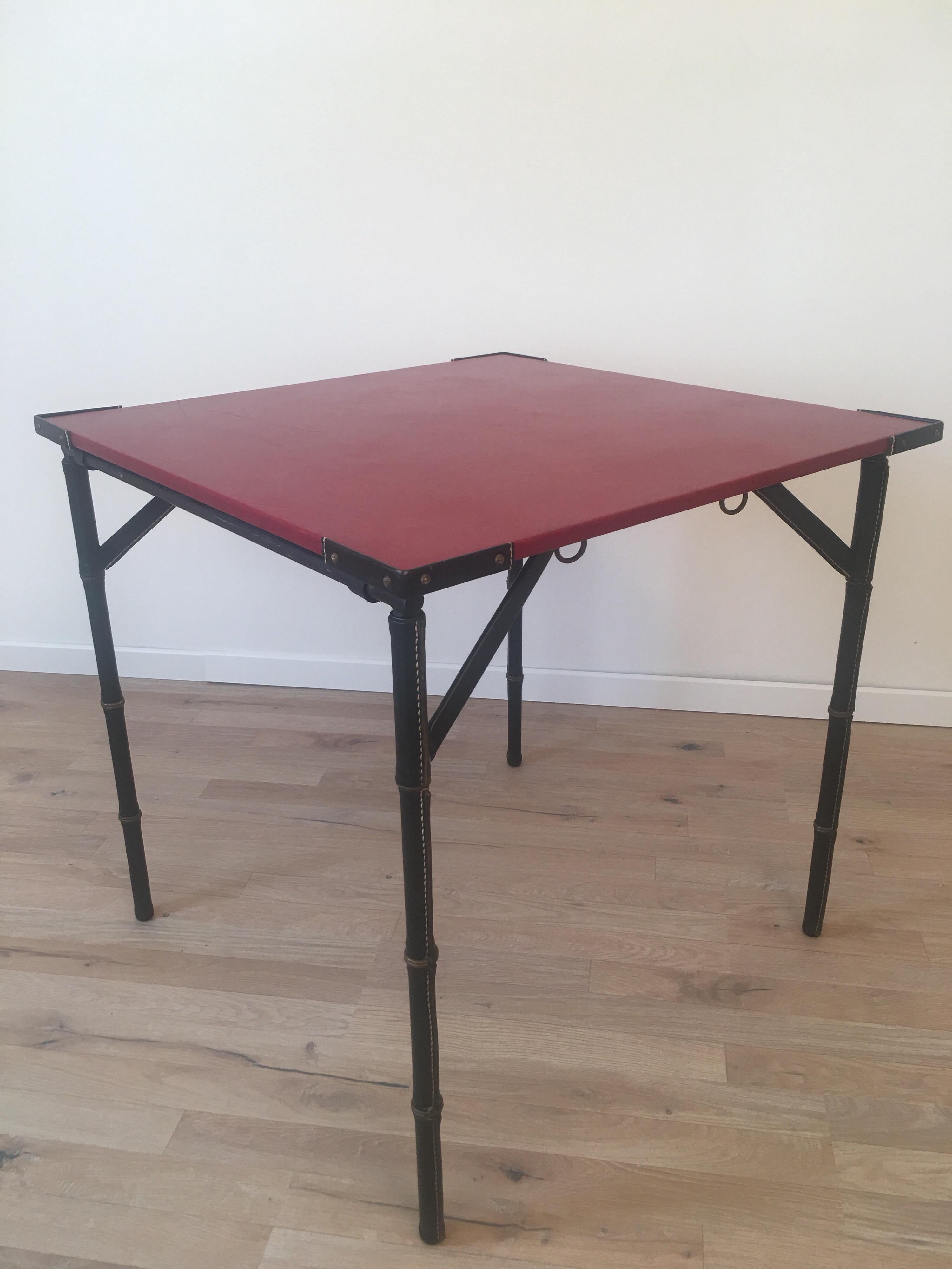 Rare red and black game table or side table designed by the famous French designer Jacques Adnet in 1950s.
Hand-stitched leather and bamboo brass design are characteristic elements of his work.
The table is very stable and completely folds down
